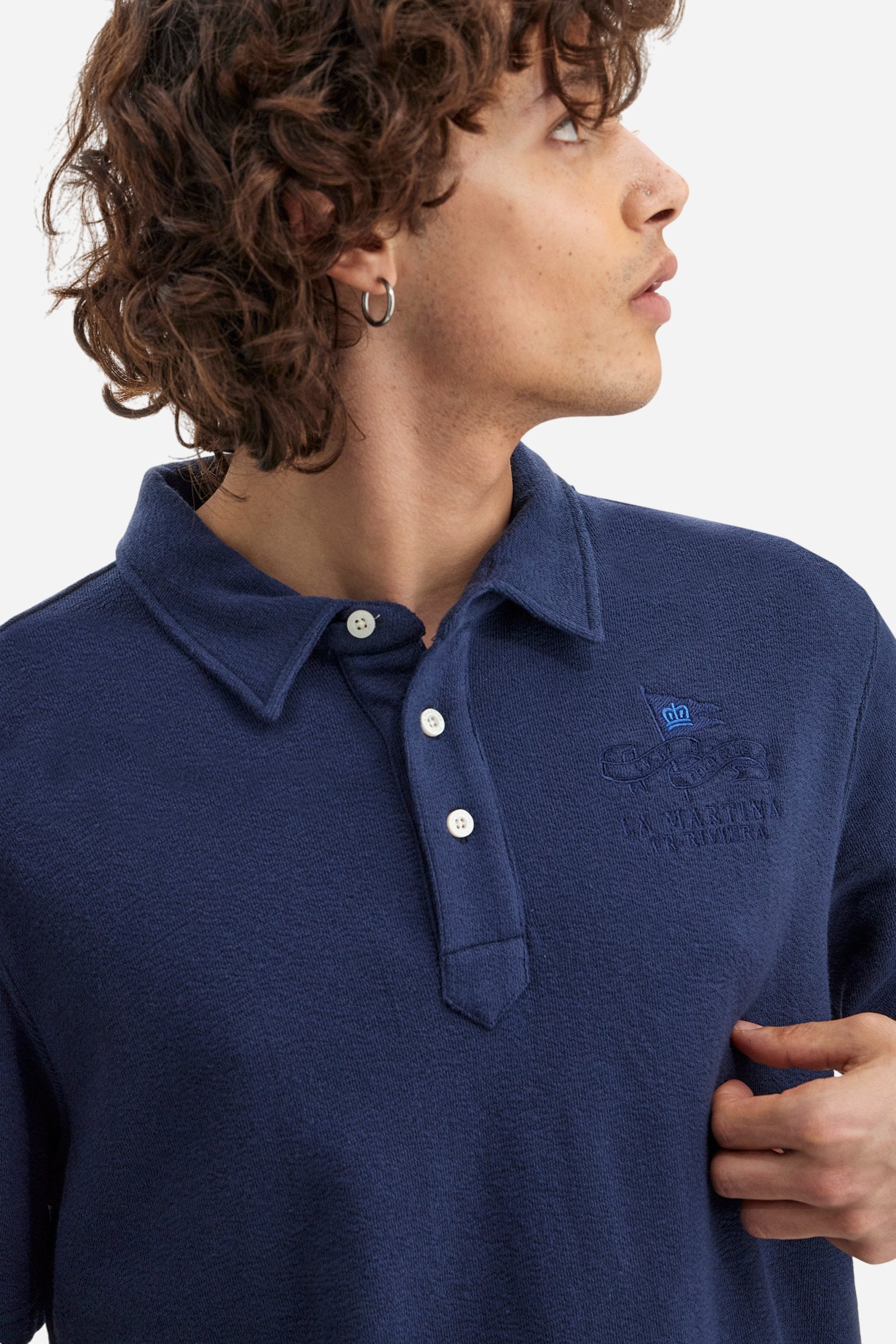 Men's plain short-sleeved polo shirt made from brushed jersey. Three-button fastening. The embroidery on the left side of the chest, in contrasting thread, is inspired by the French Riviera. A small logo is embroidered on the left sleeve, also using contrasting thread. Regular fit. The model is wearing a size L. - Navy