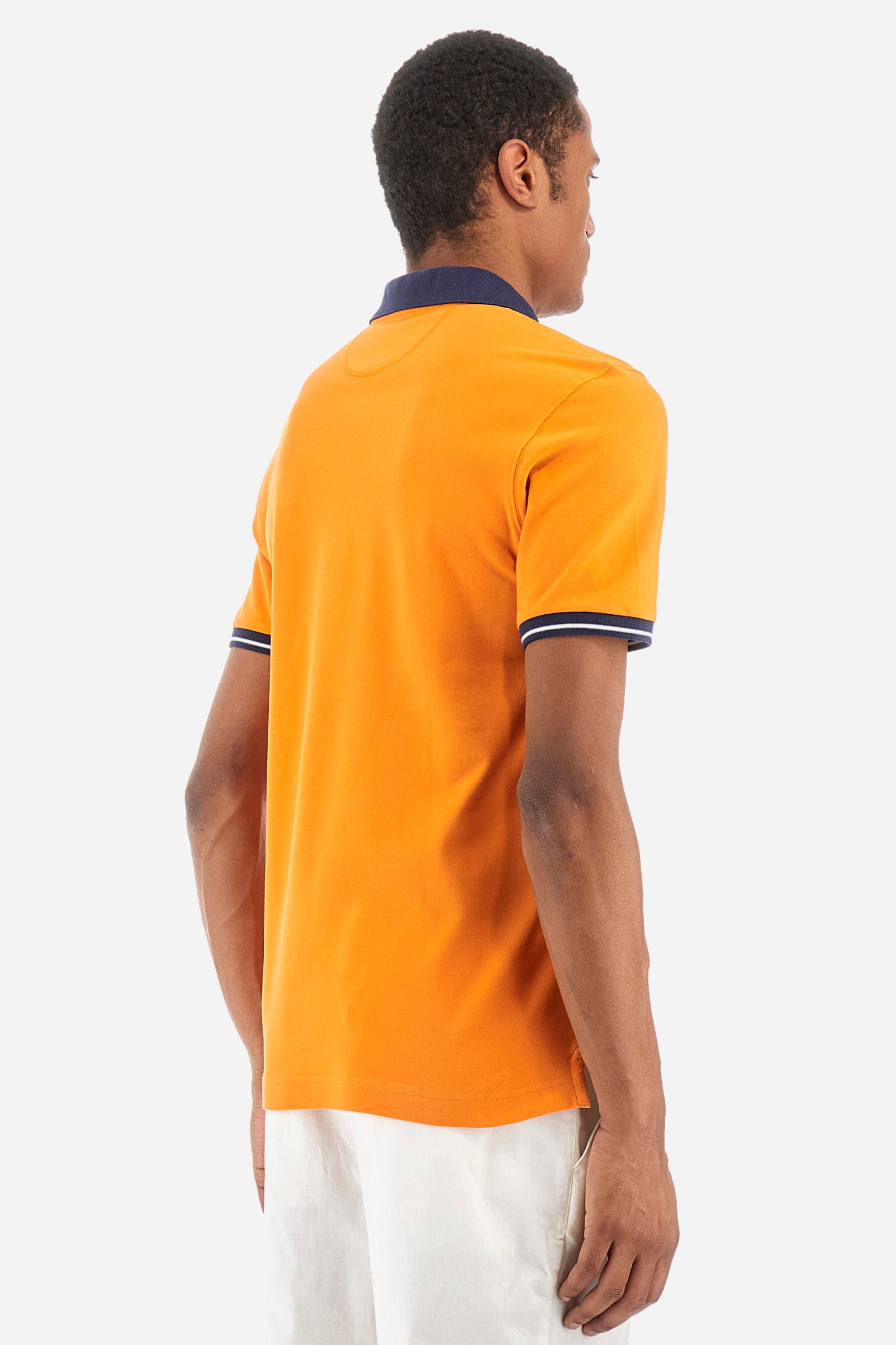 Men's single-colour short-sleeved polo in elasticated cotton. Fastens with two contrasting buttons. Ribbed collar and armholes in different shades. The "La Martina" lettering can be found under the collar. A large logo is embroidered on the chest. The fit is slim. The model wears a size L. - Celosia Orange
