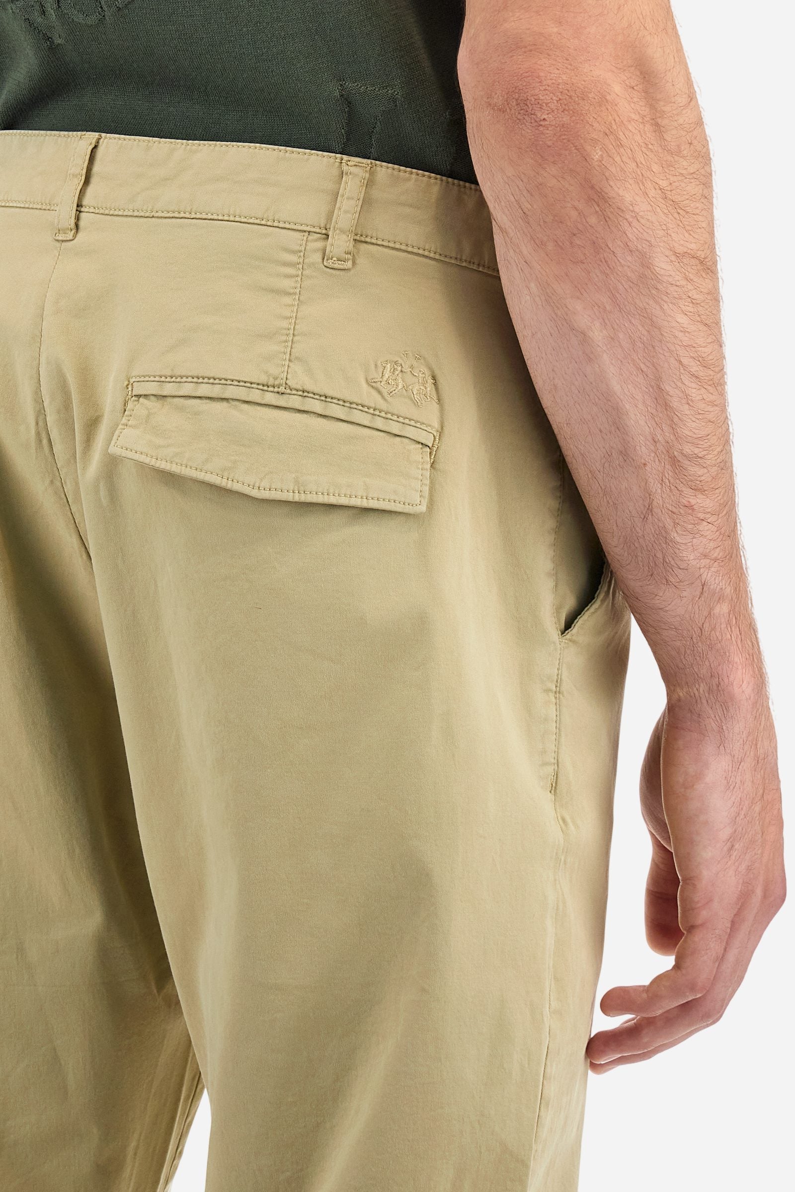 Single-colour men's chino trousers made of elasticated cotton twill. Zip fastening and faux horn button. Side slash pockets and folded waistband. On the back there are welt pockets with a flap and hidden button. The right front loop has a metal rivet with the flag of Argentina as an applied detail. Regular fit. The model is wearing a size 33. - Twill