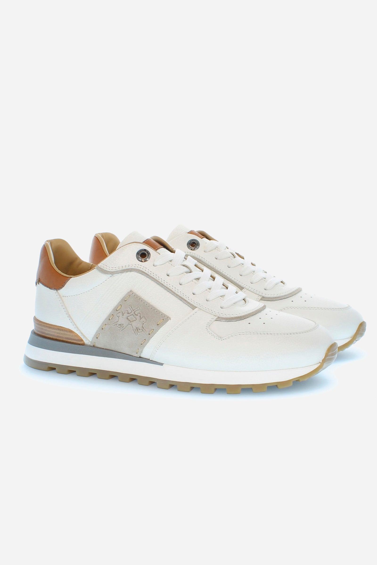 Men's calfskin trainer with hand-stitched side band in a contrasting tone, with an embossed La Martina logo. This shoe displays great attention to detail: from the contrasting lacing profile, which creates a dynamic effect, to the leather and suede inserts on the back or to the leather spoiler on the heel. The aged effect of the leather on the upper gives the shoe an unmistakably artisanal touch. Perfect for a gritty look with details that evoke the classicism of the La Martina brand. - WHITE/IVORY