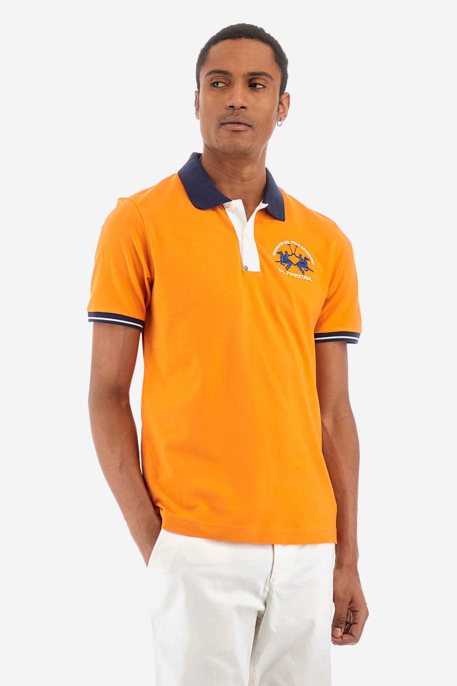 Men's single-colour short-sleeved polo in elasticated cotton. Fastens with two contrasting buttons. Ribbed collar and armholes in different shades. The "La Martina" lettering can be found under the collar. A large logo is embroidered on the chest. The fit is slim. The model wears a size L. - Celosia Orange