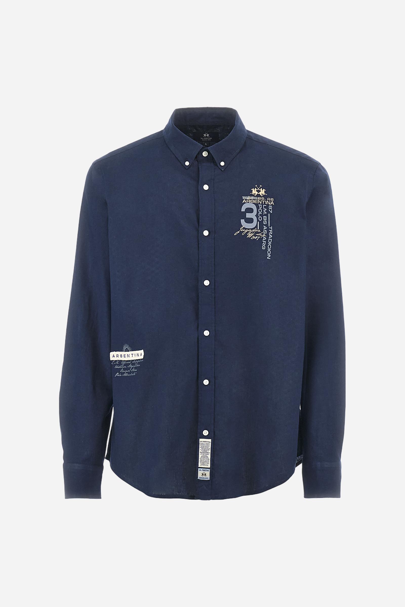 Men's plain long-sleeved shirt made from cotton and linen canvas. Featuring a button-down collar and sleeve openings embellished with contrasting fabric details. The graphic on the chest, over the heart, is created using a combination of embroidery and printing techniques to add a distinctive touch. On the side, at the front, there is a ribbon embroidered with the word Argentina, topped with a print. Regular fit. The model is wearing a size L. - Navy