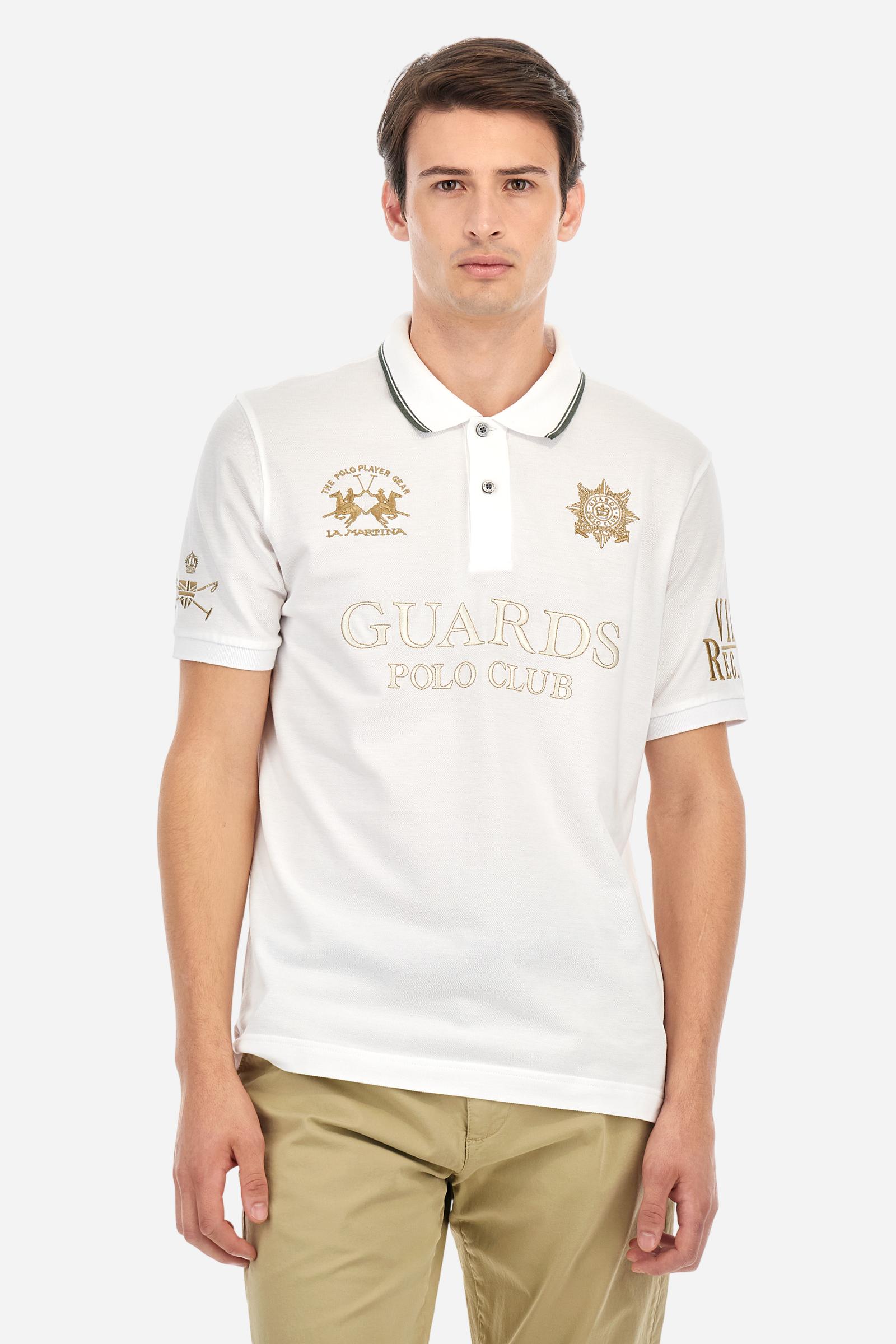 Men's short-sleeved Guards polo shirt in a single colour, made of cotton piqué. Fastens with two buttons. The collar is ribbed with striped trim in a contrasting colour. The graphics on the chest and sleeves are all made using the embroidery technique. The central lettering on the chest is a 3D embroidery in the same colour as the base fabric. The large colour-contrasting logo is embroidered on the chest. The fit is regular. The model is wearing a size L. - Optic White
