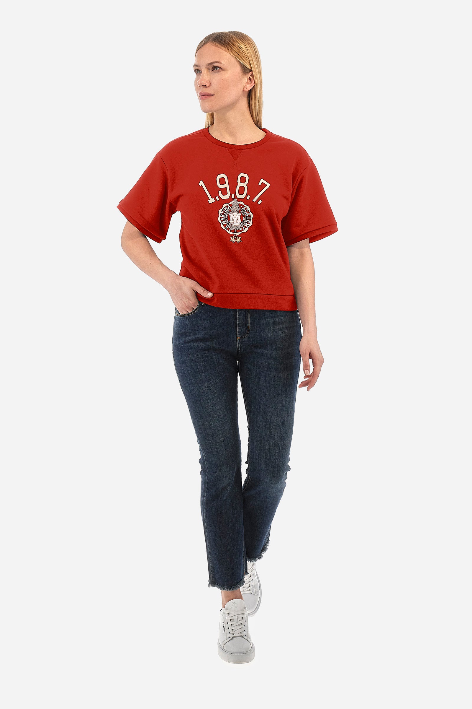 This women's cotton-blend short-sleeved crew-neck sweatshirt in a regular fit from the Polo Academy line is a comfortable choice for any occasion. The solid colour with La Martina 1987 print and logo on the front add a touch of style to your daily outfit. Thanks to the 5 buttons on the back, this sweatshirt is also practical and functional. Ideal for those looking for a versatile and quality garment. The model is 174 cm tall and wears a size 2. - Barbados Cherry