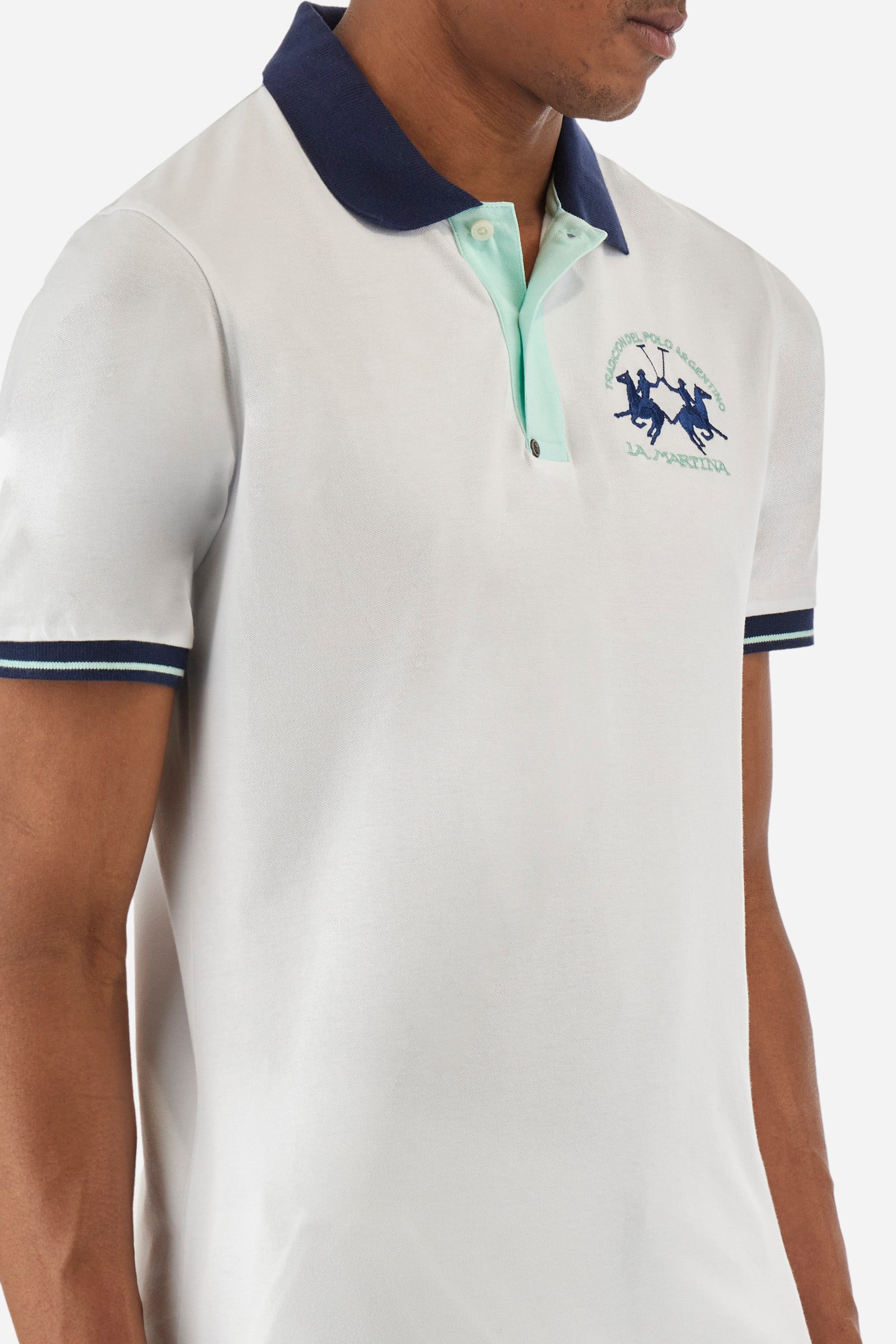 Men's single-colour short-sleeved polo in elasticated cotton. Fastens with two contrasting buttons. Ribbed collar and armholes in different shades. The "La Martina" lettering can be found under the collar. A large logo is embroidered on the chest. The fit is slim. The model wears a size L. - Optic White