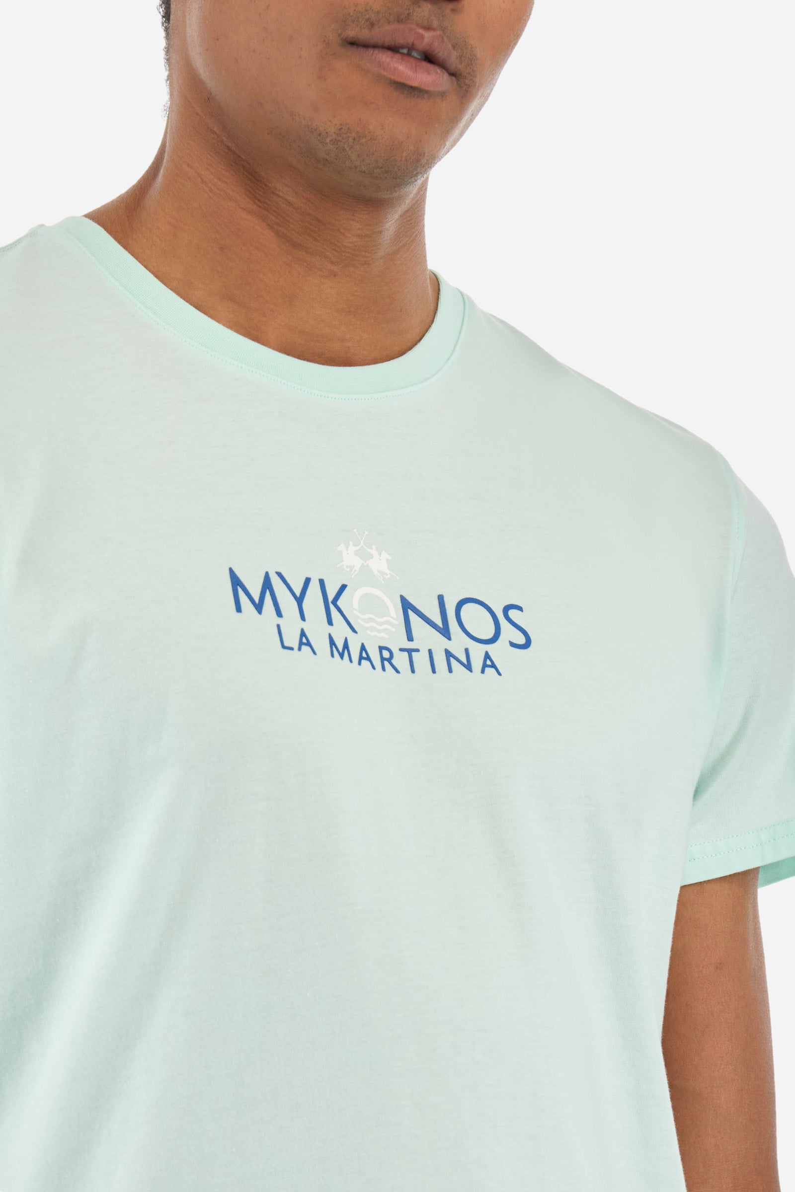 Men's short-sleeved T-shirt with a crew neck in a single colour. Made of 100% cotton. Printed on the front are the words "Mykonos" and "La Martina". On the back we find stylised prints inspired by Greece and the lettering that is also present on the front. Regular fit. The model wears a size L. - Honeydew