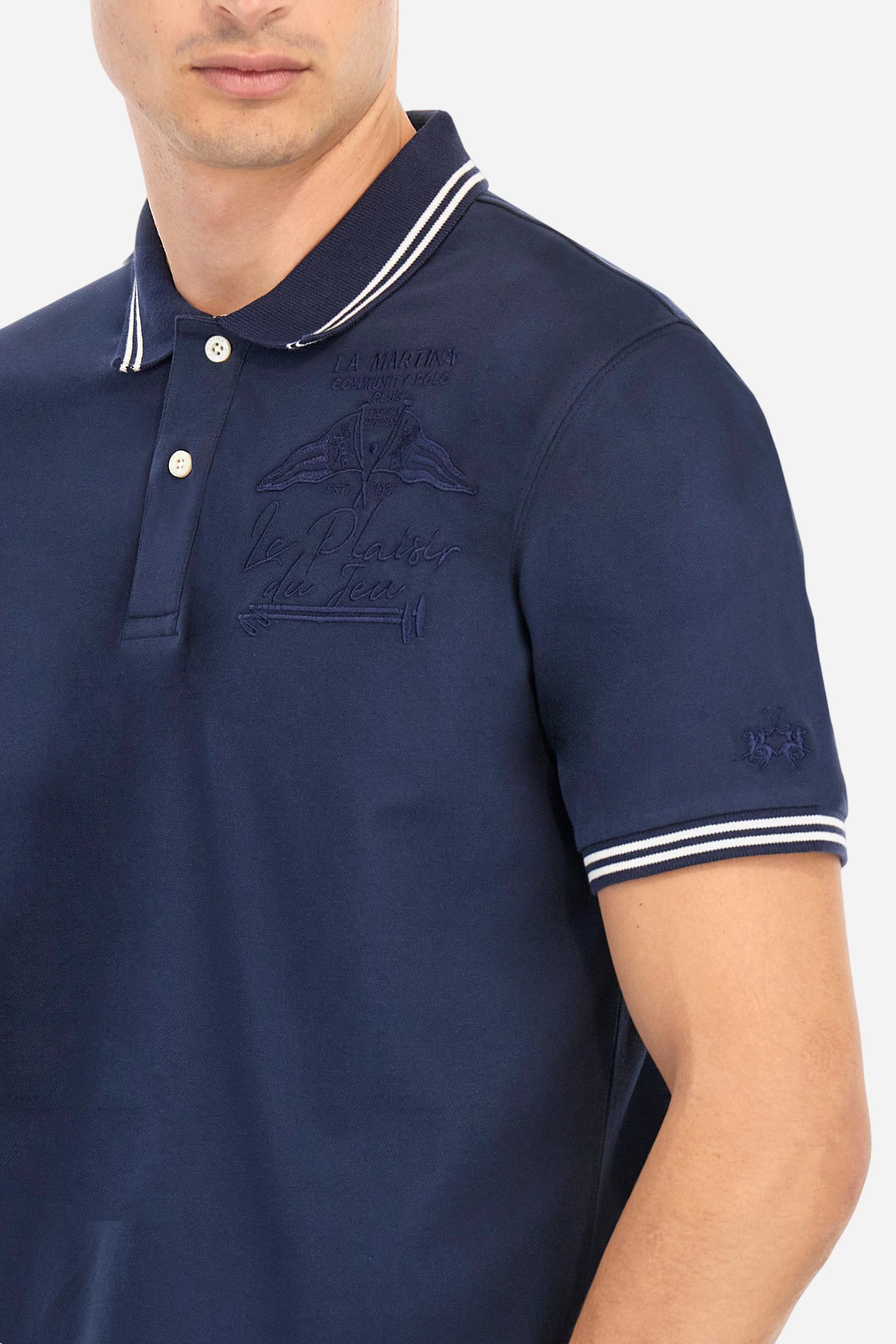 Men's plain short-sleeved polo shirt made from stretch piqué. Two-button fastening. The collar and cuffs are made from two-tone striped ribbed fabric. The inside of the collar and placket feature contrasting fabrics and colours. There is a two-tone striped band around the inside of the collar. The right sleeve and chest are embroidered in tone-on-tone thread. A logo is embroidered on the left sleeve, also using tone-on-tone thread. Regular fit. The model is wearing a size L. - Navy