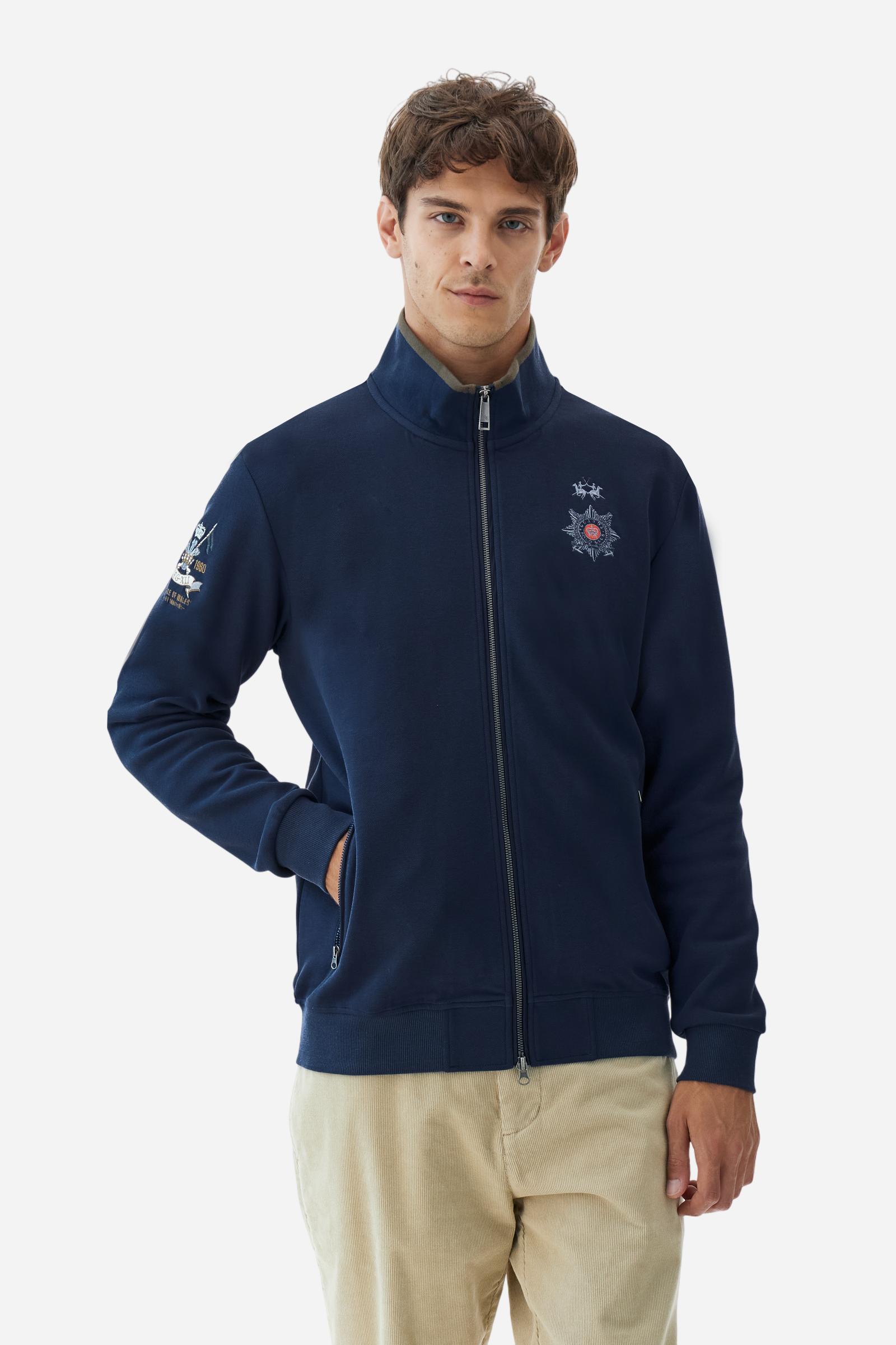 Men's long-sleeved, full-zip solid colour sweatshirt. Made of stretch cotton-blend piqué. Design with front opening fastened by a zip, high collar in two-tone ribbing. Solid colour ribbed cuffs and waistband. The small brand logo and Guards crest are embroidered in multi-coloured thread on the chest. On the right sleeve, there is another embroidery of a crest inspired by the British royal household. The regular fit silhouette is practical for everyday wear. The model is wearing a size L. - Navy