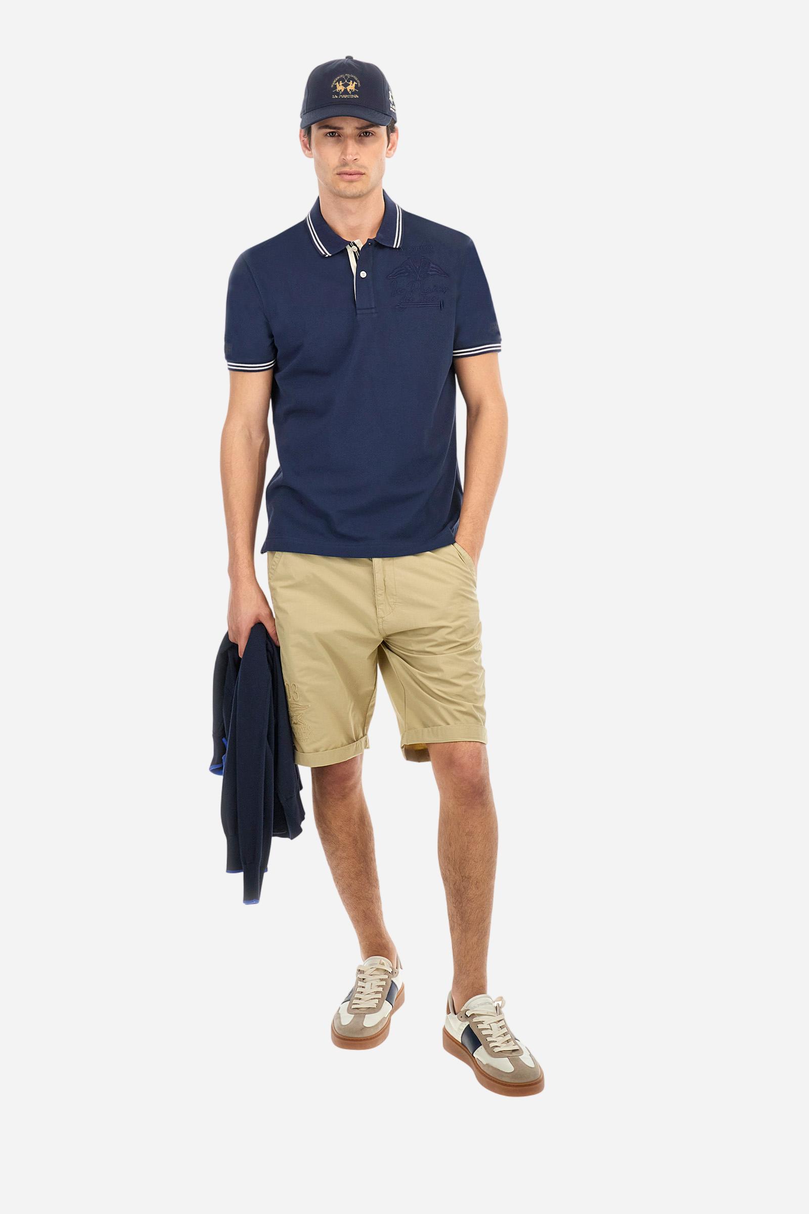 Men's plain short-sleeved polo shirt made from stretch piqué. Two-button fastening. The collar and cuffs are made from two-tone striped ribbed fabric. The inside of the collar and placket feature contrasting fabrics and colours. There is a two-tone striped band around the inside of the collar. The right sleeve and chest are embroidered in tone-on-tone thread. A logo is embroidered on the left sleeve, also using tone-on-tone thread. Regular fit. The model is wearing a size L. - Navy