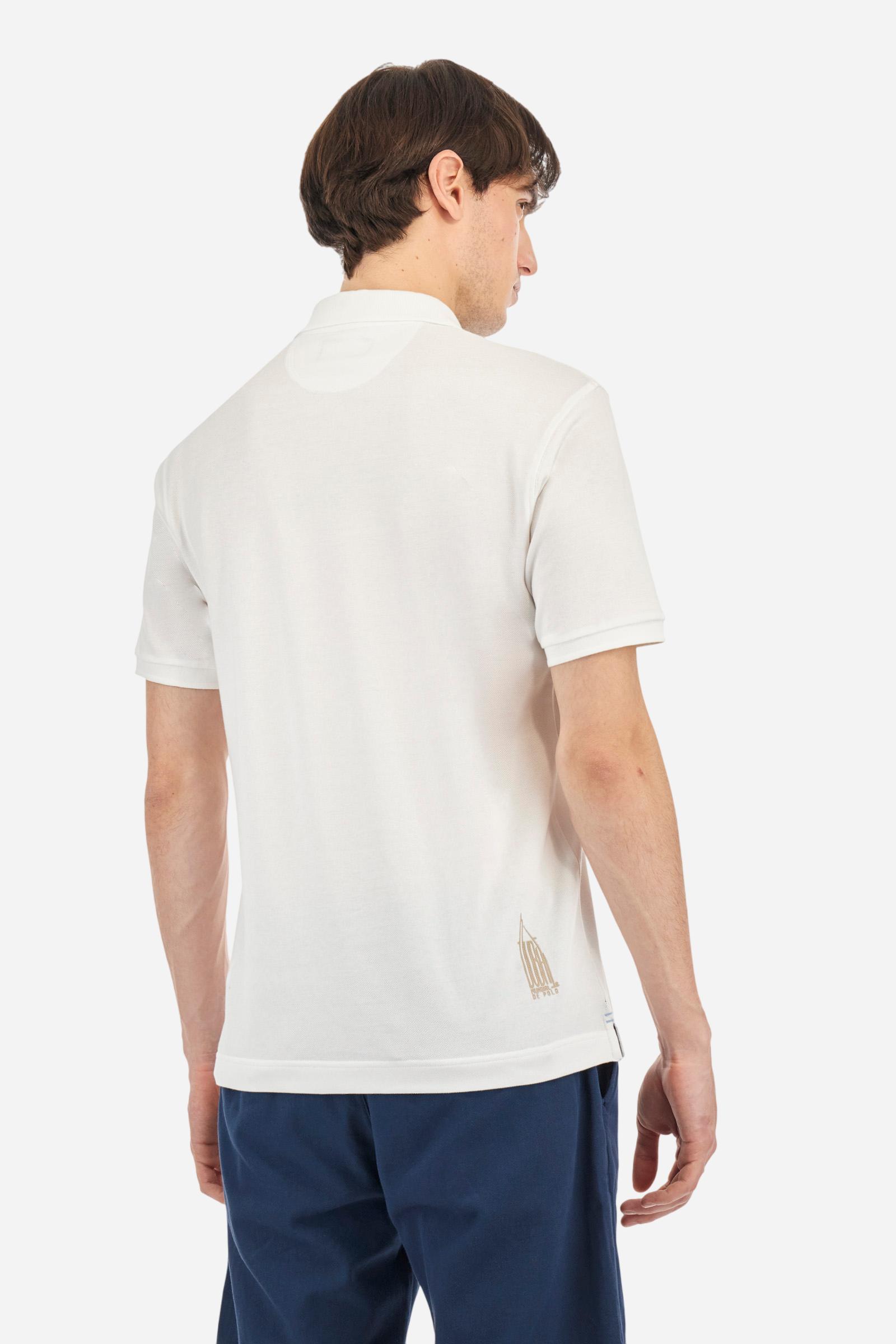 Men's plain short-sleeved polo shirt made from cotton piqué. Two-button fastening. The collar and cuffs are made from tone-on-tone ribbed fabric. The inside of the placket is also made from piqué, but in a contrasting colour. On the left side of the chest, in addition to the embroidered logo in contrasting thread, there are small patches of the Argentine and English flags. Regular fit. The model is wearing a size L. - Optic White