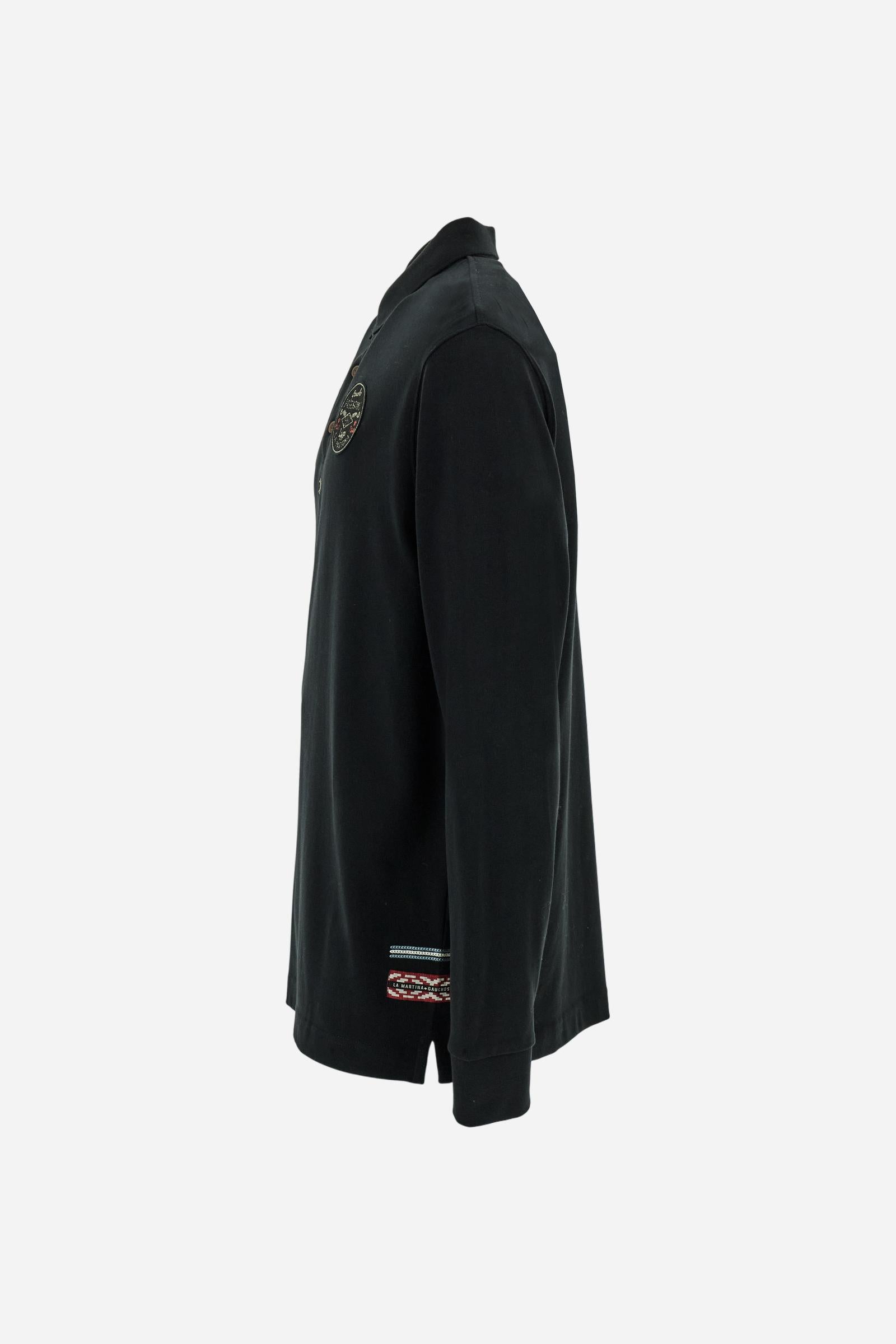 Long-sleeve polo shirt crafted from 100% high-quality cotton jersey. The velvety fabric offers a warm, cozy feel, perfect for cooler seasons. Ribbed collar and cuffs in matching tone, with a three-button personalized placket. A small multicolor embroidered logo sits below the opening, while tonal patches in different shapes and textures, inspired by Argentine culture and Gaucho tradition, decorate the chest and back. Classic regular fit. Model wears size L. - Black