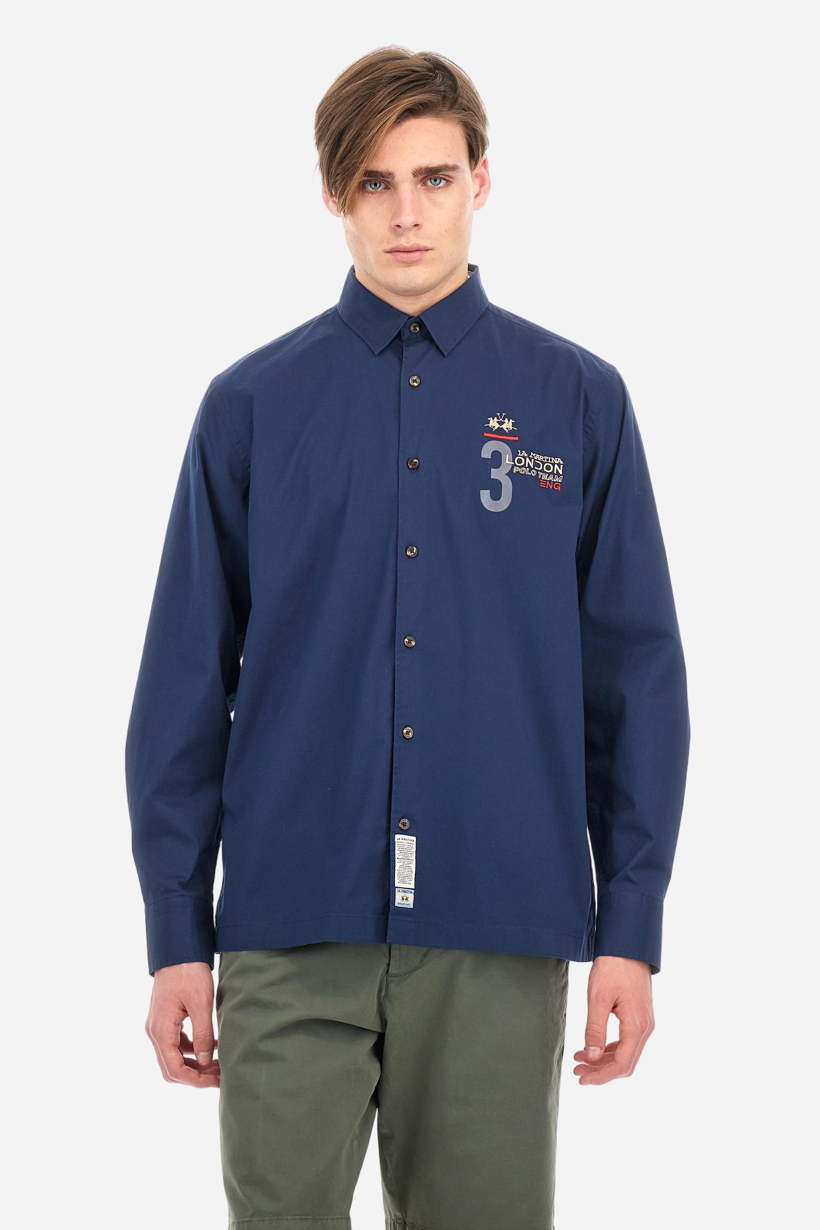 Men's single-colour long-sleeved shirt, made from 100% cotton poplin. Spread collar. Contrasting printed fabric details on the inside of the collar and opening. The numbers on the chest and back graphics are rubberised prints, while the rest of the graphics are embroidered. The logo and La Martina lettering is embroidered on the left chest. The fit is regular. The model is wearing a size L. - Navy