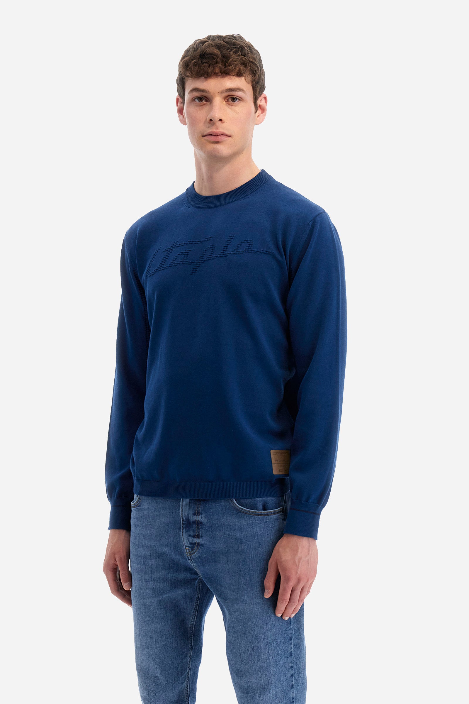 Men's long-sleeved crew-neck jumper in a single colour in collaboration with Pagani. Made from 100% cotton. Some parts of the garment have a woven basket stitch texture. Ribbed cuffs, neck and waist. The front features the line's characteristic lettering. The logo and "La Martina" and "Pagani" lettering are present on the patch representing the collaboration applied on both the front and back. The fit is regular. The model wears a size L. - Ensign Blue
