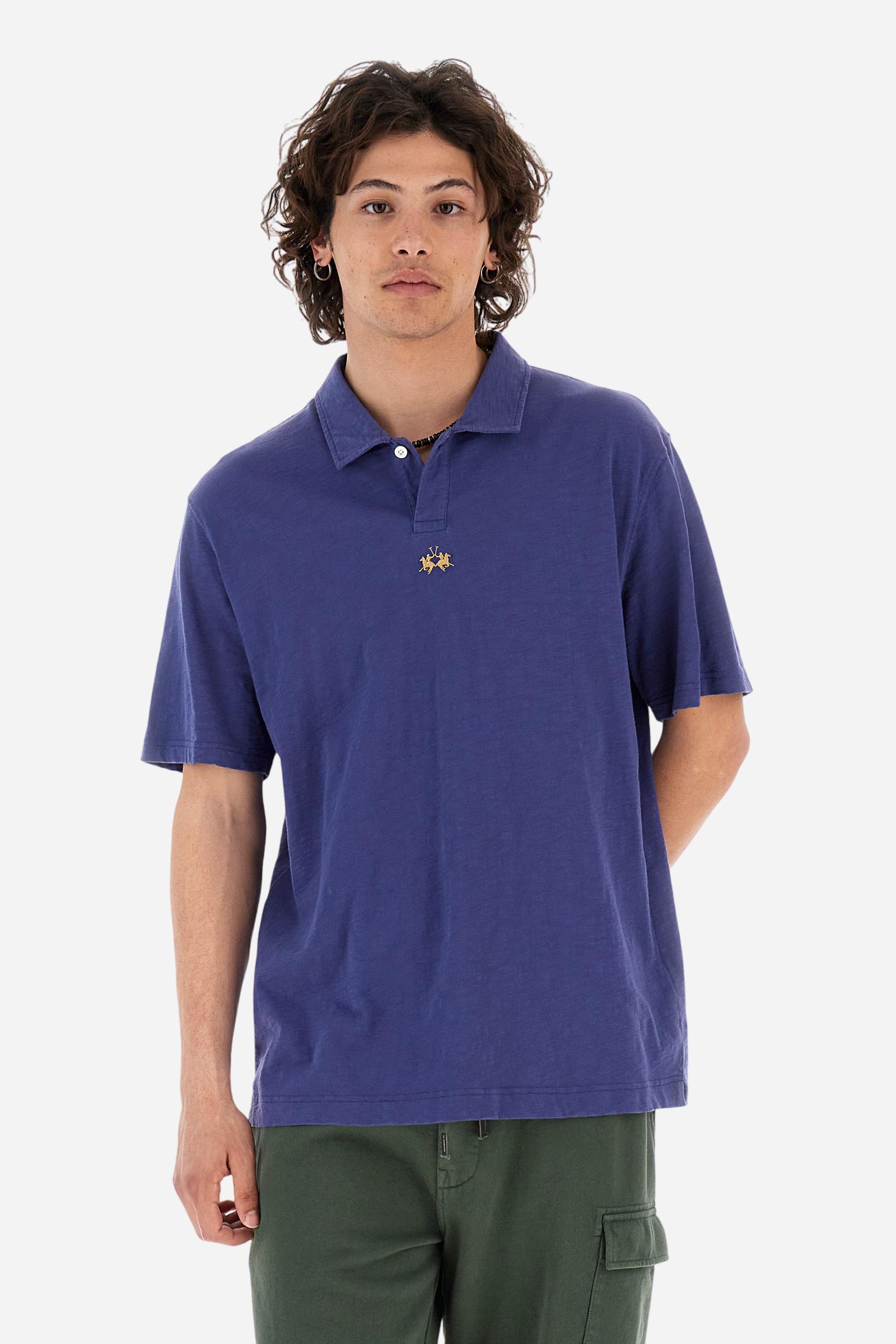 Men's short-sleeved polo shirt in a single colour, made of 100% cotton slub jersey. Fastens with a button. A fabric patch representing the garment's certificate is sewn onto the back. The logo is embroidered in contrast under the opening on the front. Comfort fit. The model is wearing a size L. - Deep Cobalt