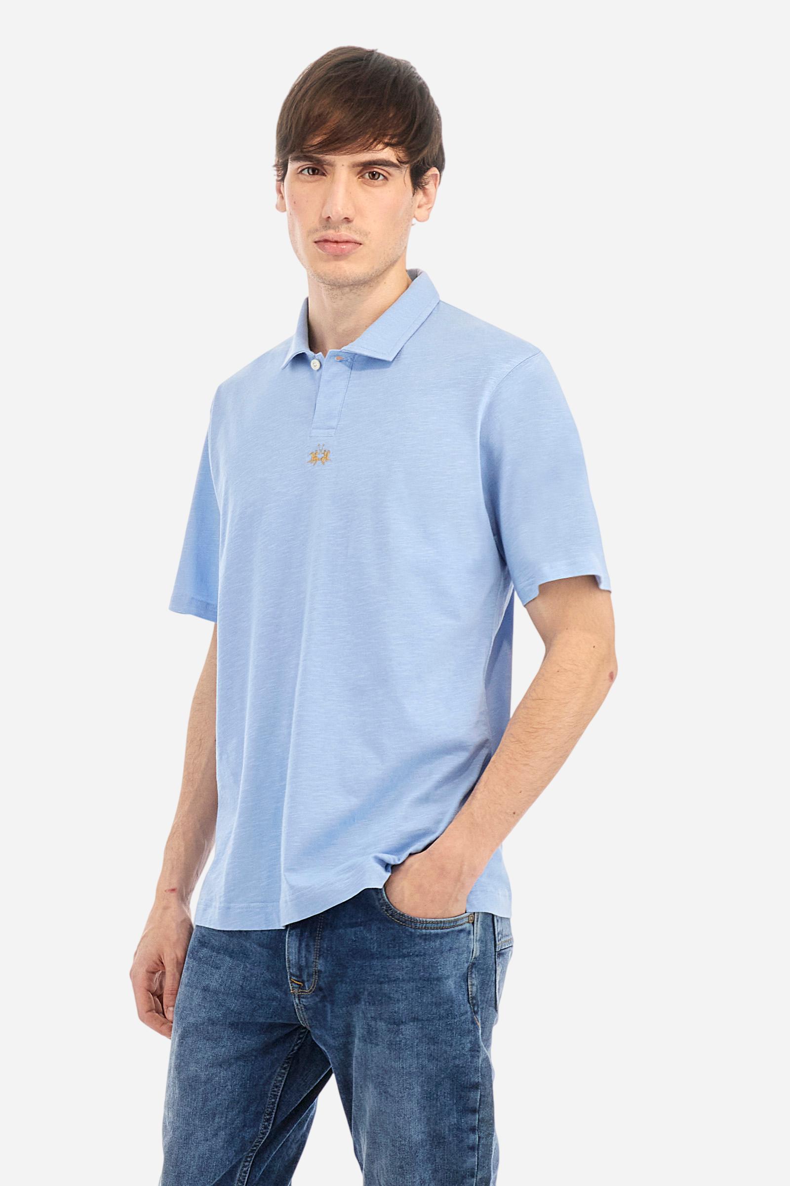 Men's short-sleeved polo shirt in a single colour, made of 100% cotton slub jersey. Fastens with a button. A fabric patch representing the garment's certificate is sewn onto the back. The logo is embroidered in contrast under the opening on the front. Comfort fit. The model is wearing a size L. - Vista Blue