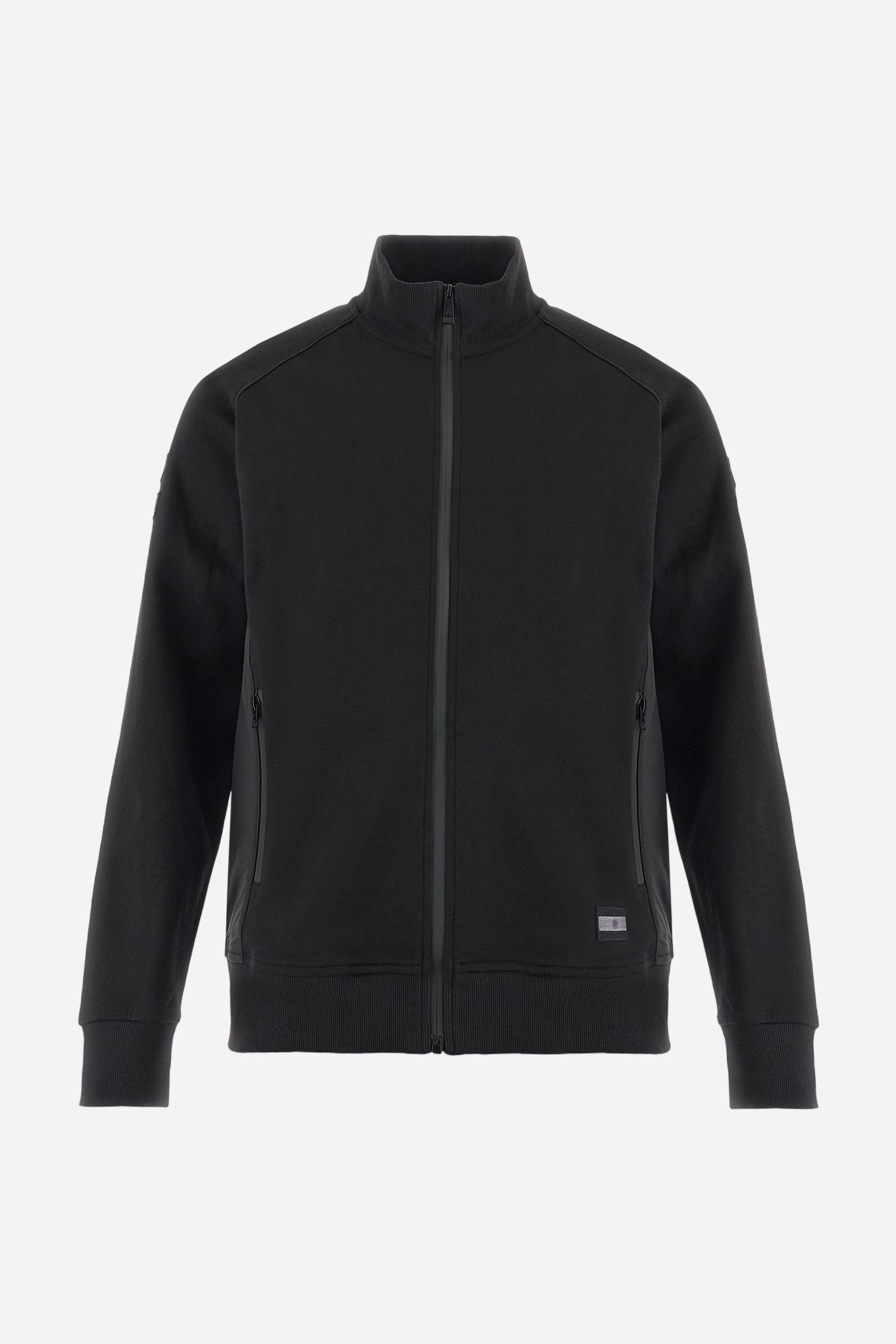 Men's long-sleeved sweatshirt in solid cotton-blend interlock with semi-glossy finish. Features customised front zip, stand-up collar, hem and cuffs in tone-on-tone rib. Large semi-gloss La Martina transfer on the back celebrates the brand's identity, while two patches on the right sleeve recall the Argentine polo association. Regular fit for a practical yet refined style. Model wears size L. - Black