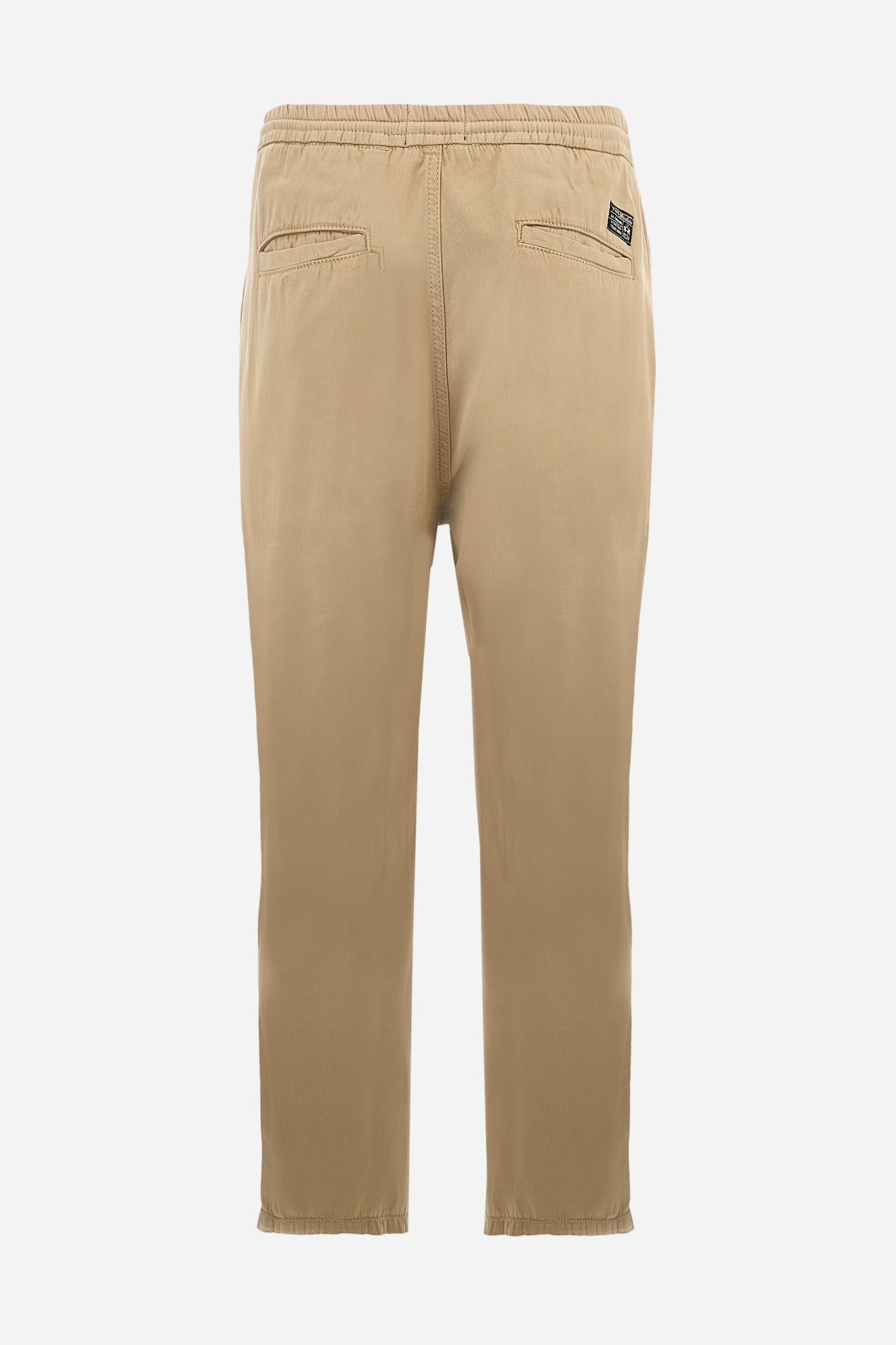 Men's plain straight-cut trousers, made of linen and cotton canvas. Featuring a waist belt at the back and on the sides with elasticated external drawstring for adjustment. The front opening also has a faux horn button on the belt and a zip. Double welt pocket inserted into the sides. There are two additional welt pockets on the back. The logo is featured on the woven label sewn above the right back pocket. Regular fit. The model is wearing a size L. - Twill