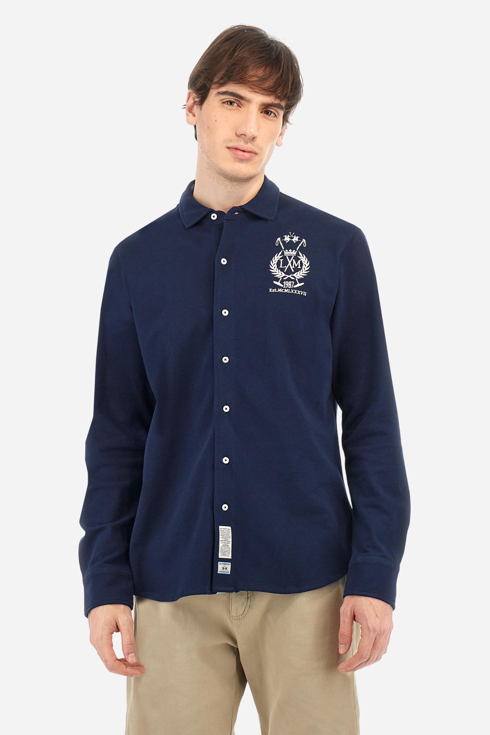 Men's plain long-sleeved shirt made from cotton piqué. It features an elegant spread collar and a seamless front opening, with no visible stitching. A graphic is embroidered on the chest, over the heart, in contrasting thread. Regular fit. The model is wearing a size L. - Navy