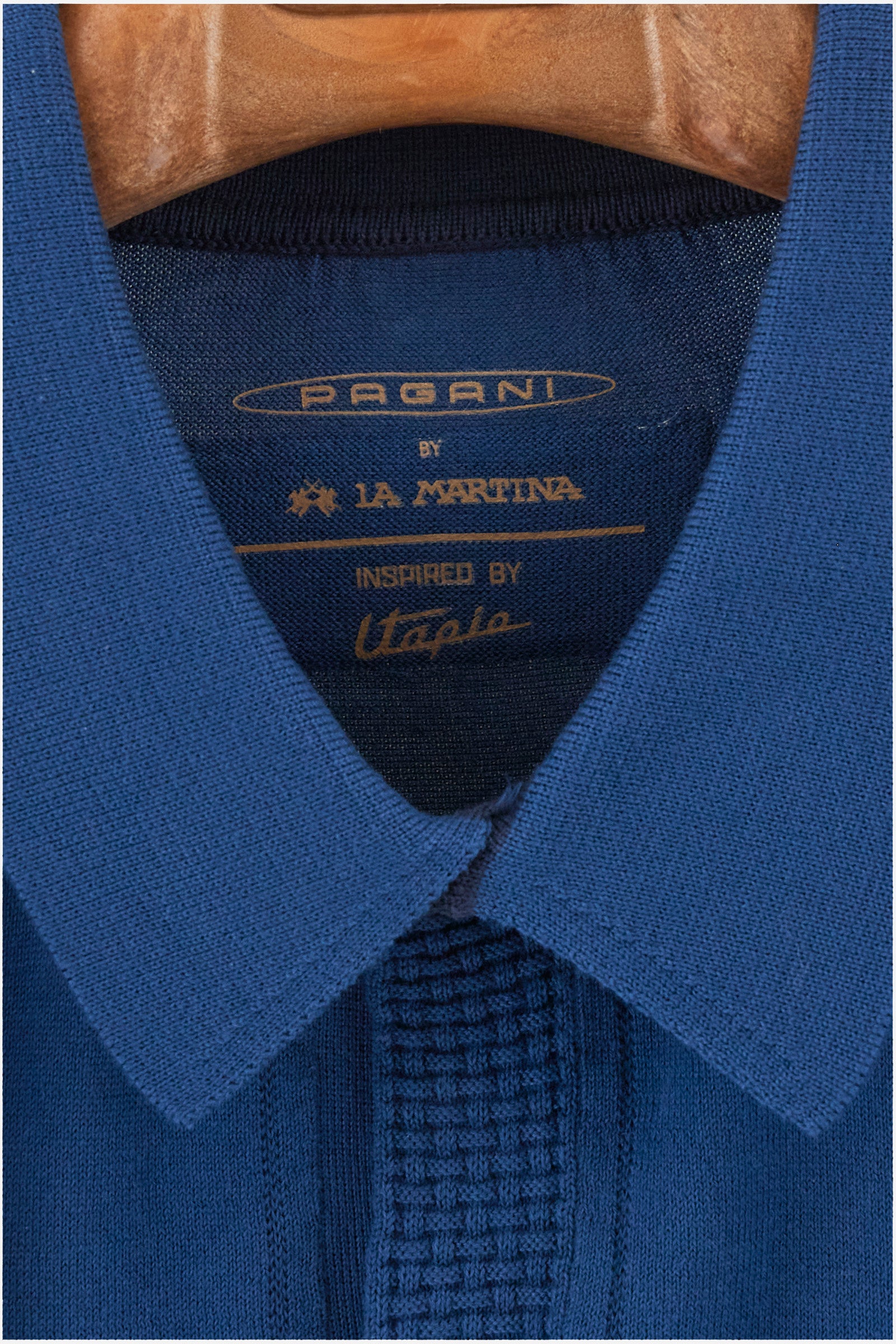 Single-colour men's knitted polo shirt with short sleeves from the line in collaboration with Pagani. Made of 100% cotton. Fastens with a button. Ribbed armholes and waist. The logo and "La Martina" and "Pagani" lettering are present on the patch representing the collaboration applied on the back. The fit is regular. The model wears a size L. - Ensign Blue