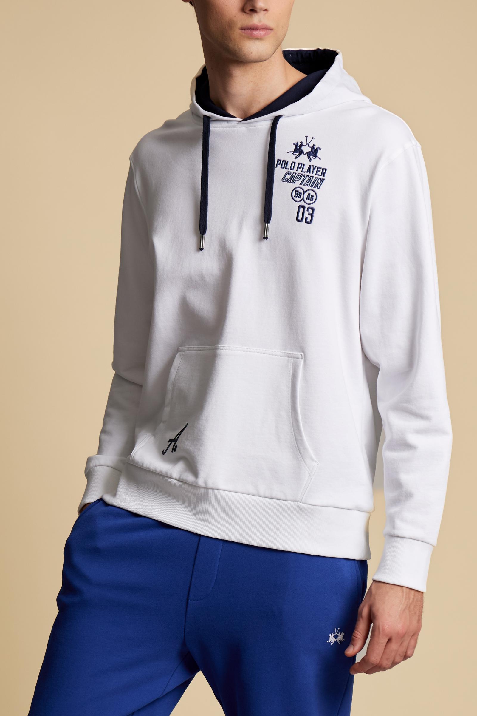 Men’s long-sleeve cotton French terry sweatshirt with a contrast jersey-lined hood, ribbed cuffs, navy embroidery, and a bold Argentina print on the back. - Optic White