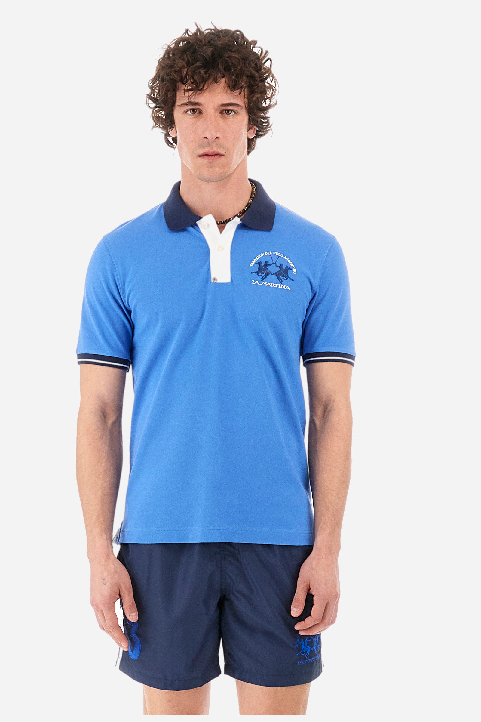 Men's single-colour short-sleeved polo in elasticated cotton. Fastens with two contrasting buttons. Ribbed collar and armholes in different shades. The "La Martina" lettering can be found under the collar. A large logo is embroidered on the chest. The fit is slim. The model wears a size L. - Campanula
