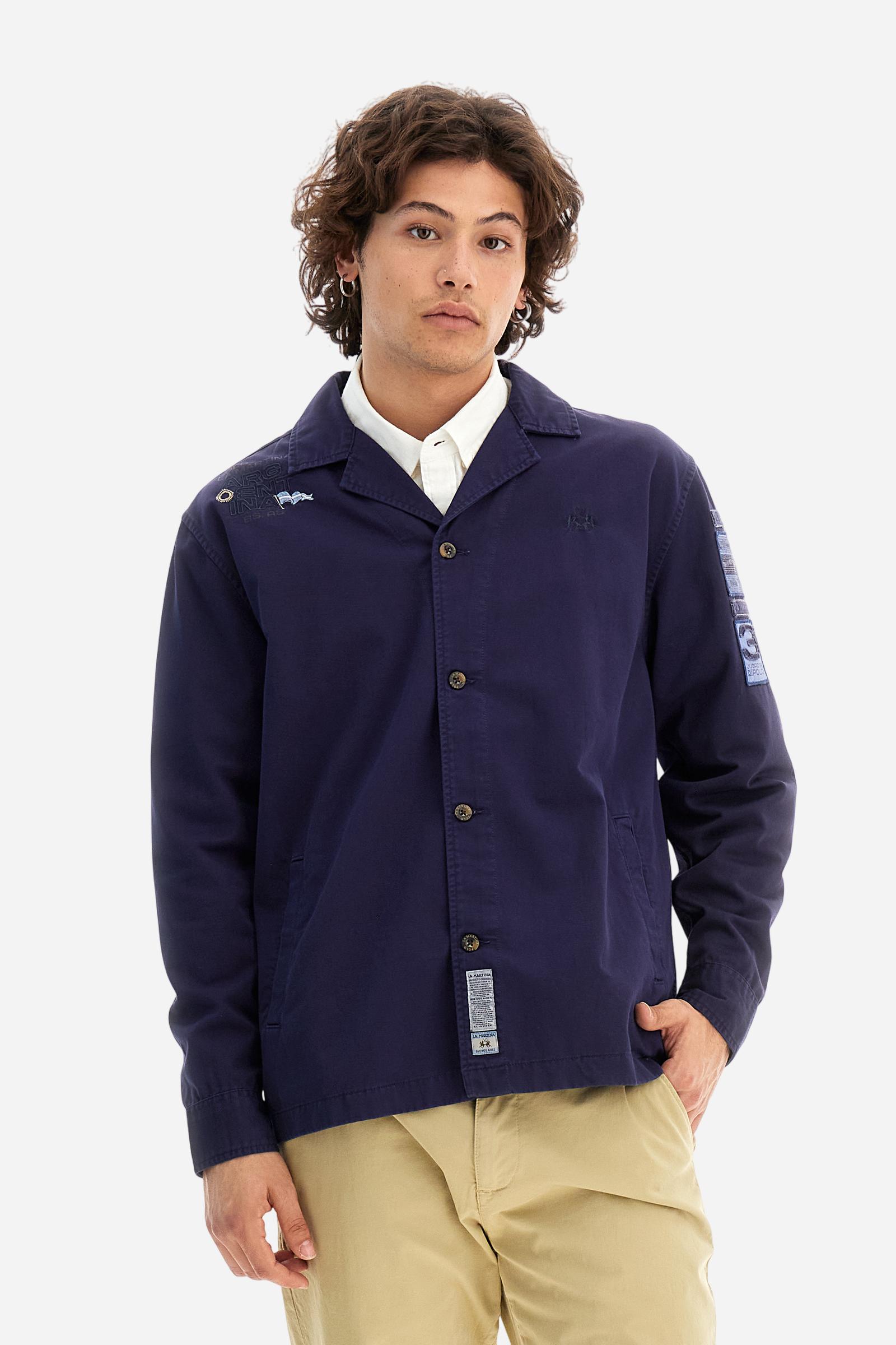 Men's single-colour long-sleeved overshirt made of 100% cotton slub twill. Bowling collar and jacket opening with inside placket, fastening with imitation horn buttons.On the shoulder and chest the embroidery is in tone with the garment, Argentina lettering embroidered on one shoulder. There are several patches applied on the left sleeve. A tone-on-tone logo is embroidered on the front. Regular fit. The model is wearing a size L. - Deep Cobalt