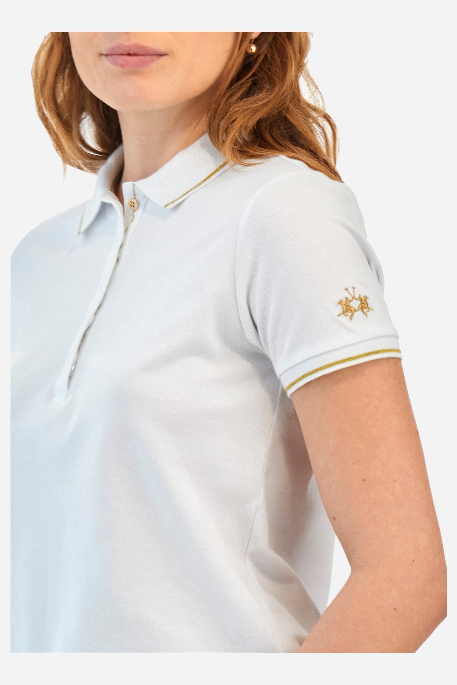 Women’s polo with short sleeves in solid color, made of stretch cotton. 5-button closure. Collar and crew sleeves profiled and ribbed. Side slits. Under the collar there is the inscription "La Martina". The logo is embroidered on a sleeve and embellished with the application of some rhinestones. The fit is regular. The model wears a size 2. - Optic White