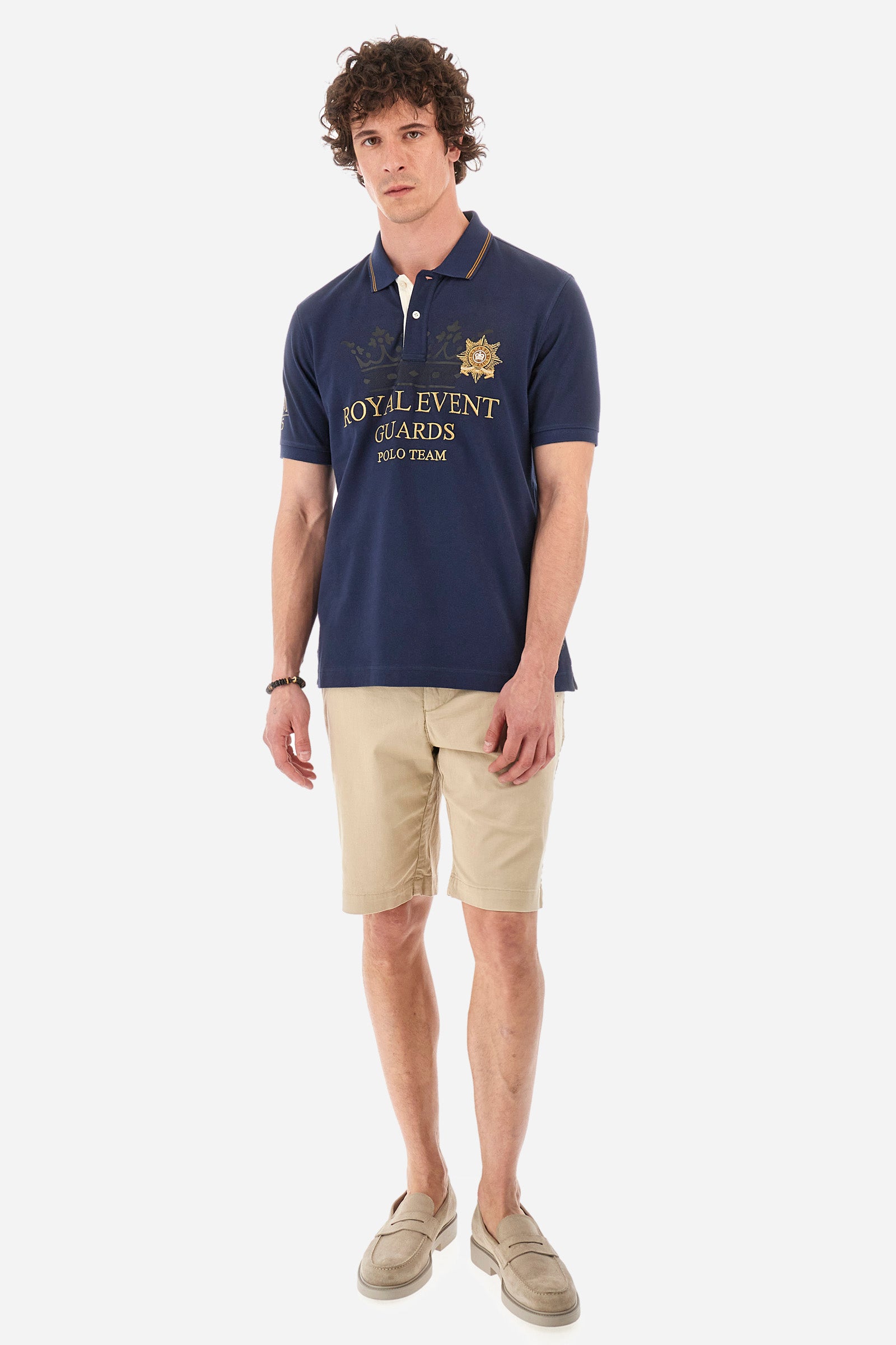 Men's single-colour short-sleeved polo shirt in 100% cotton. Two-button fastening. Collar with two contrasting stripes and ribbed armholes. On the front we find lettering and the symbol representing the Guards line. The brand's initials, the number 55 and the logo are embroidered on one of the sleeves. The fit is regular. The model wears a size L. - Navy