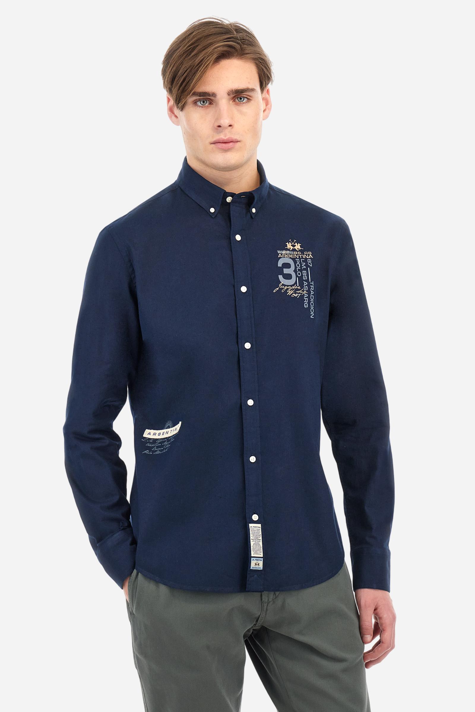 Men's plain long-sleeved shirt made from cotton and linen canvas. Featuring a button-down collar and sleeve openings embellished with contrasting fabric details. The graphic on the chest, over the heart, is created using a combination of embroidery and printing techniques to add a distinctive touch. On the side, at the front, there is a ribbon embroidered with the word Argentina, topped with a print. Regular fit. The model is wearing a size L. - Navy
