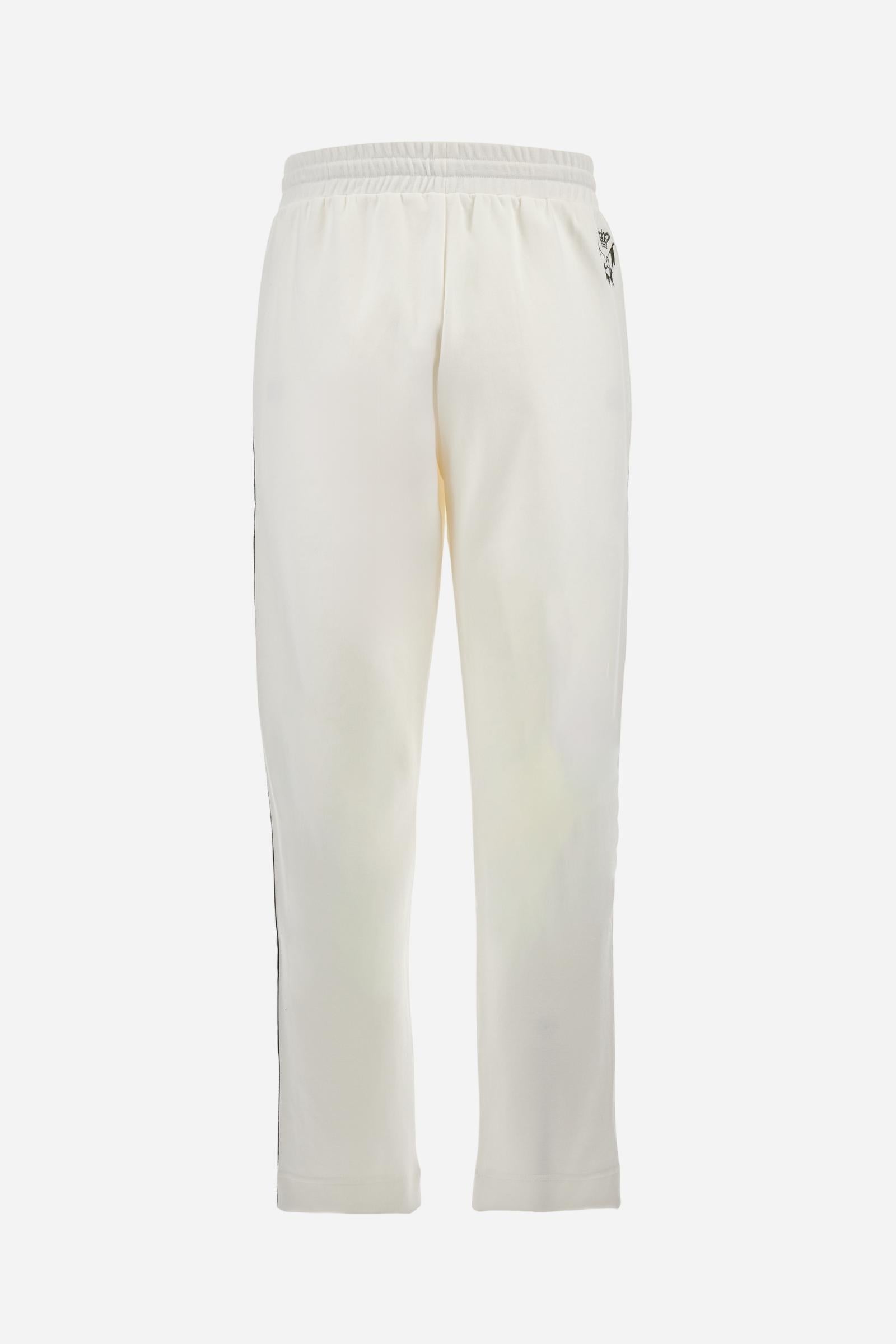 Single-colour men's jogging trousers made of lightweight cotton-blend interlock fleece. Drawstring waistband. Side pockets with matching zip fastening. On both sides, there are multicoloured striped jersey bands. The front features vertical ribbed detailing. The logo is embroidered in colour-contrasting thread on the back, under the strap, towards the right side. Regular fit. The model is wearing a size L. - Off White