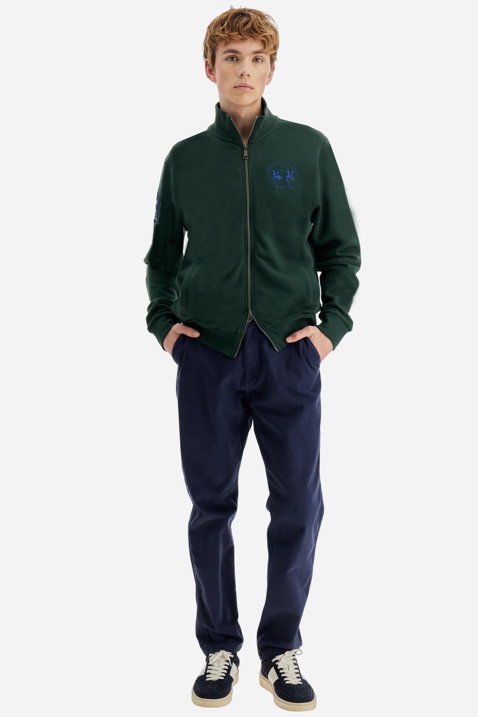 Men's long-sleeved solid colour sweatshirt. It is made of comfortable 100% cotton fleece with a soft-brushed feel. Model with high ribbed neck and front zip opening. Solid colour ribbed cuffs and waistband. The large contrasting brand team logo is embroidered on the chest. A contrasting colour fabric number patch is applied to the right sleeve. The model has a regular fit that offers a comfortable, relaxed silhouette. The model is wearing a size L. - Sycamore