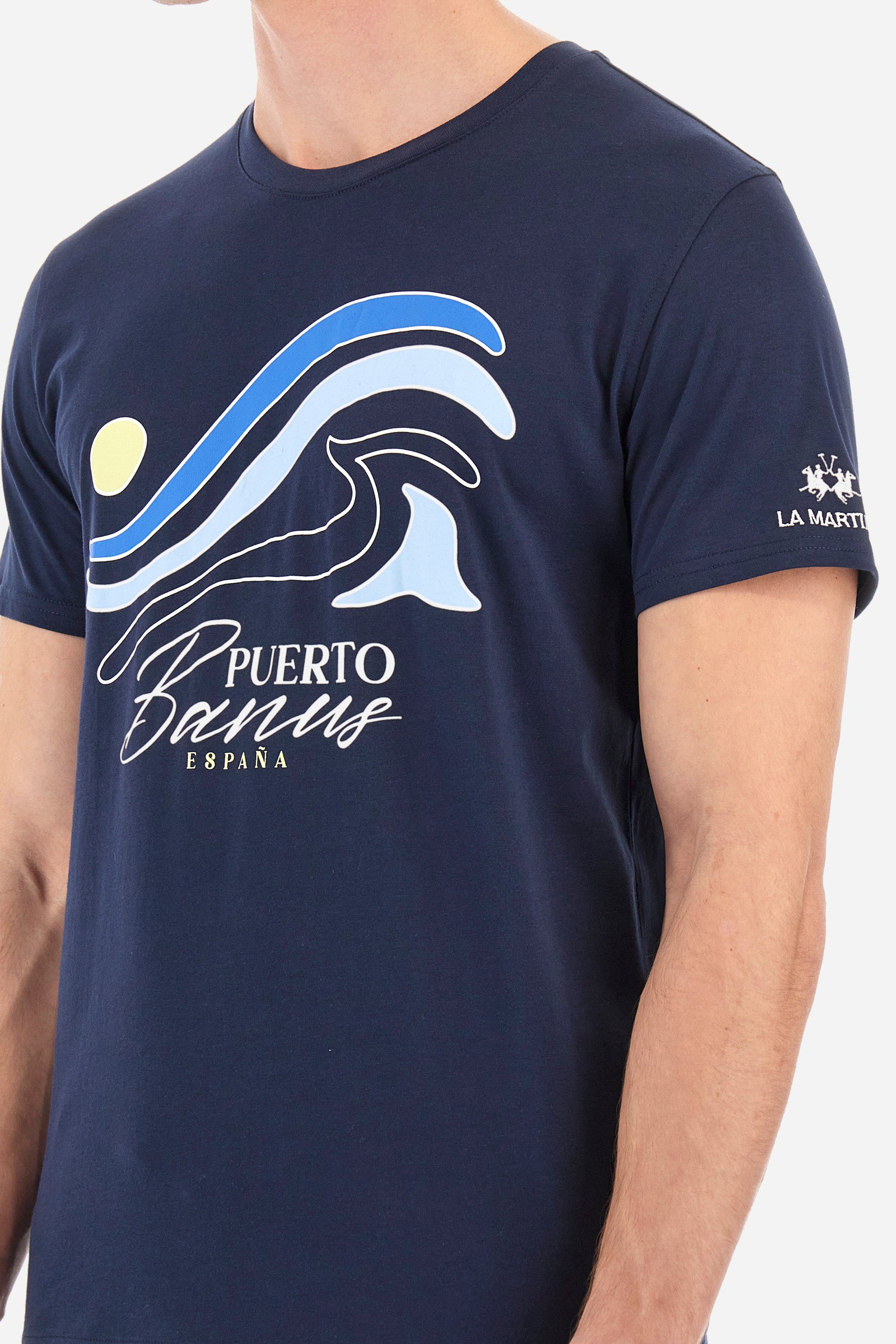 Men's short-sleeved T-shirt with a crew neck in a single colour. Made of 100% cotton. On the front there are stylised waves and the words "Puerto Banus España". A logo and the lettering "La Martina" are embroidered on one of the sleeves. Regular fit. The model wears a size L. - Navy