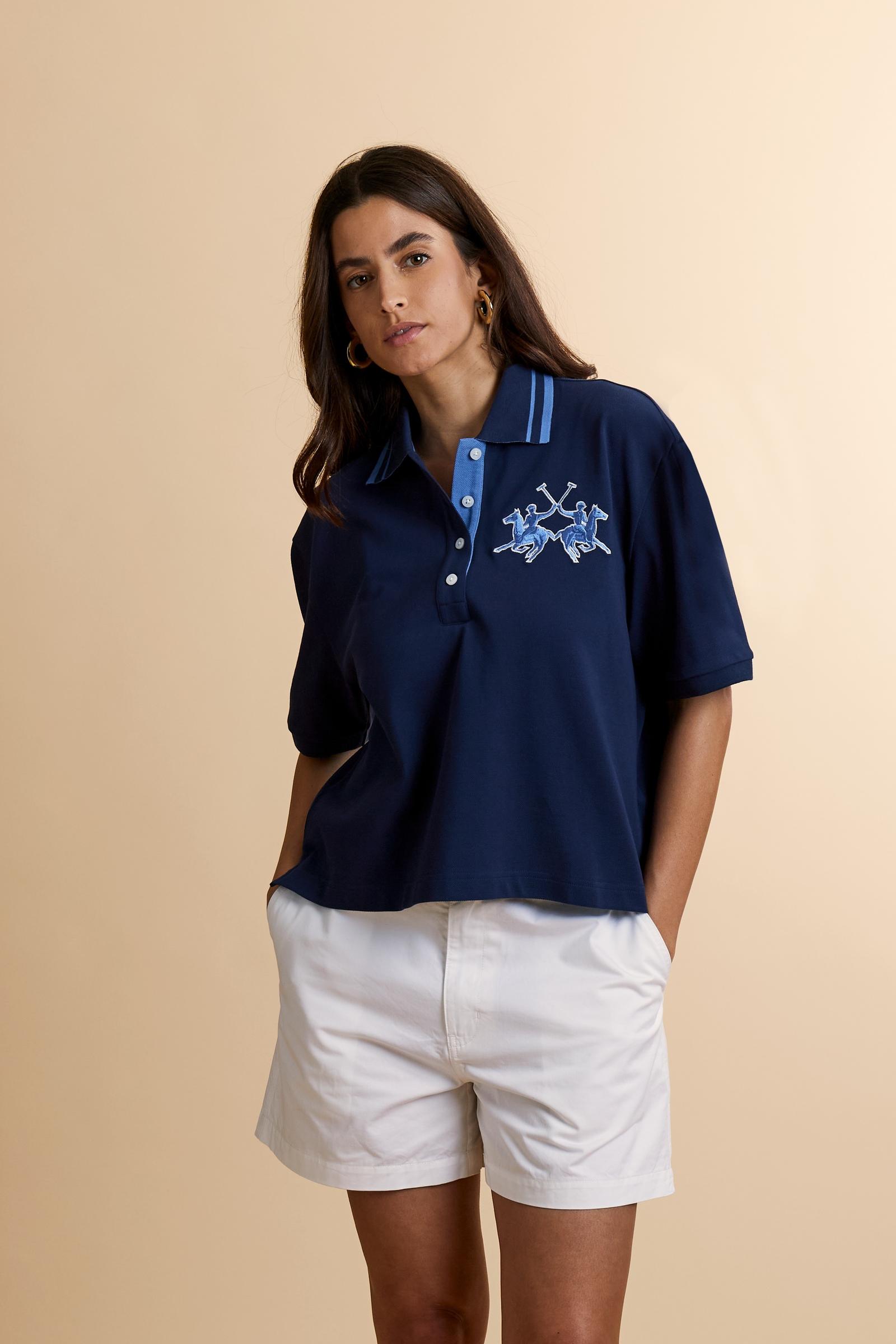 Women's short-sleeve polo shirt made from 100% cotton piqué fabric in solid color. The model features a front opening with customized buttons and a contrasting inner placket. The ribbed collar is two-tone with a striped detail creating a positive/negative color effect between the upper and lower parts. The modern fit features a slightly boxy cropped cut. The chest is decorated with a maxi 3D embroidered logo in contrasting color. The model is wearing size 2. - Navy