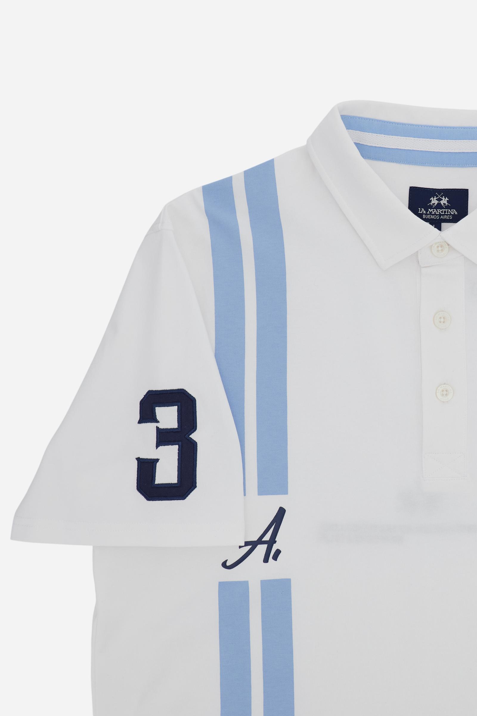 Men’s heavy cotton jersey polo with three-button placket and striped details. Celebratory maxi graphic and bold lettering. - Optic White