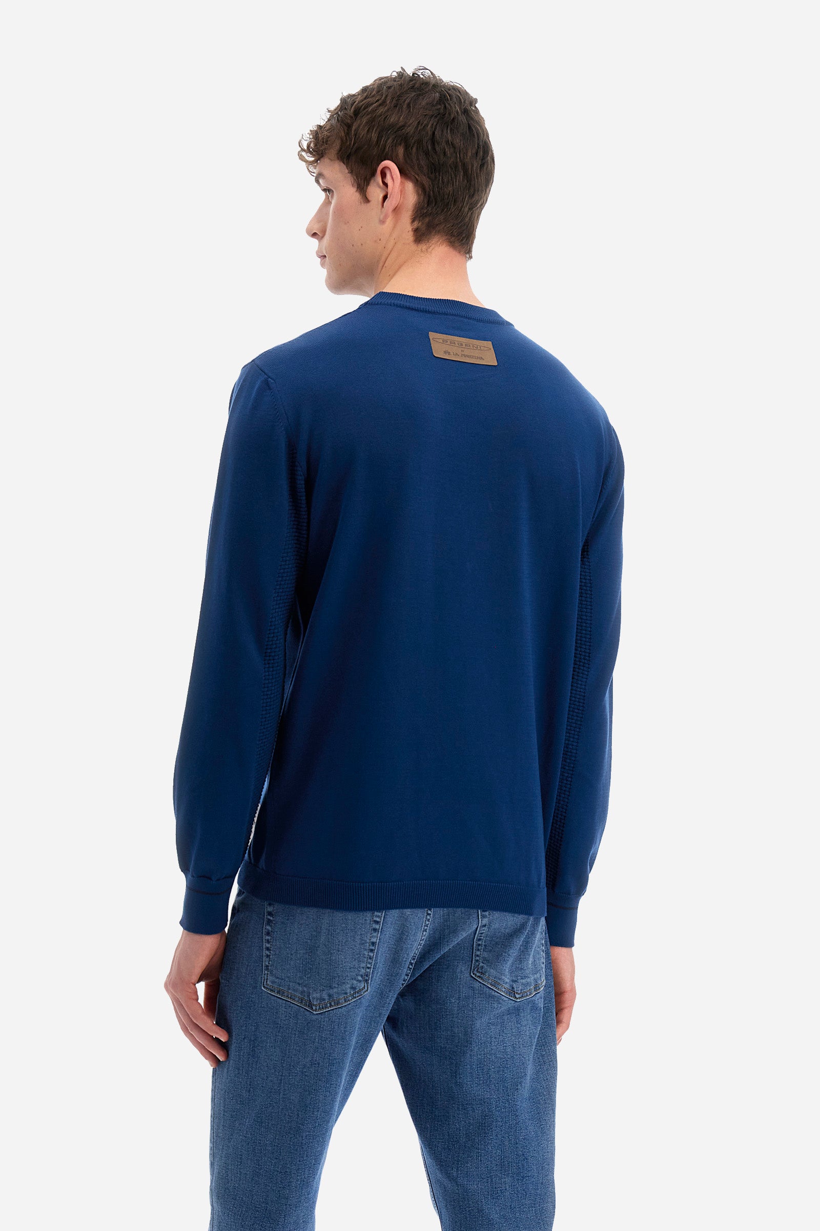 Men's long-sleeved crew-neck jumper in a single colour in collaboration with Pagani. Made from 100% cotton. Some parts of the garment have a woven basket stitch texture. Ribbed cuffs, neck and waist. The front features the line's characteristic lettering. The logo and "La Martina" and "Pagani" lettering are present on the patch representing the collaboration applied on both the front and back. The fit is regular. The model wears a size L. - Ensign Blue