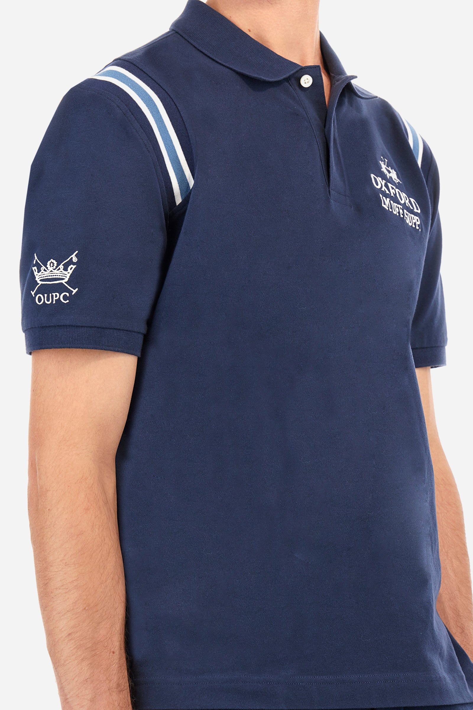 Men's short-sleeved polo shirt in plain stretch cotton. Two-button fastening. The sleeves are finished with contrasting stripes. The logo and lettering associated with the Oxford line are embroidered on the front. Regular fit. The model is wearing a size L. - Navy