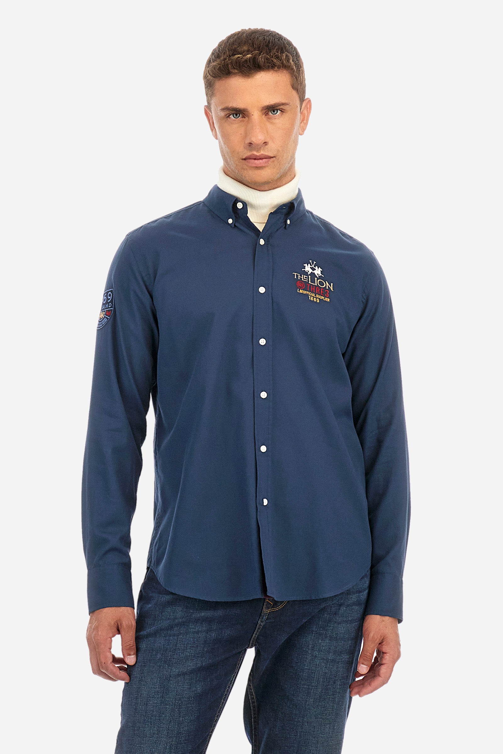 Men's plain long-sleeved shirt, made from 100% cotton. Button-down collar. The brand logo and name are embroidered on the front, alongside another iconic symbol. Regular fit. The model is wearing a size L. - Navy