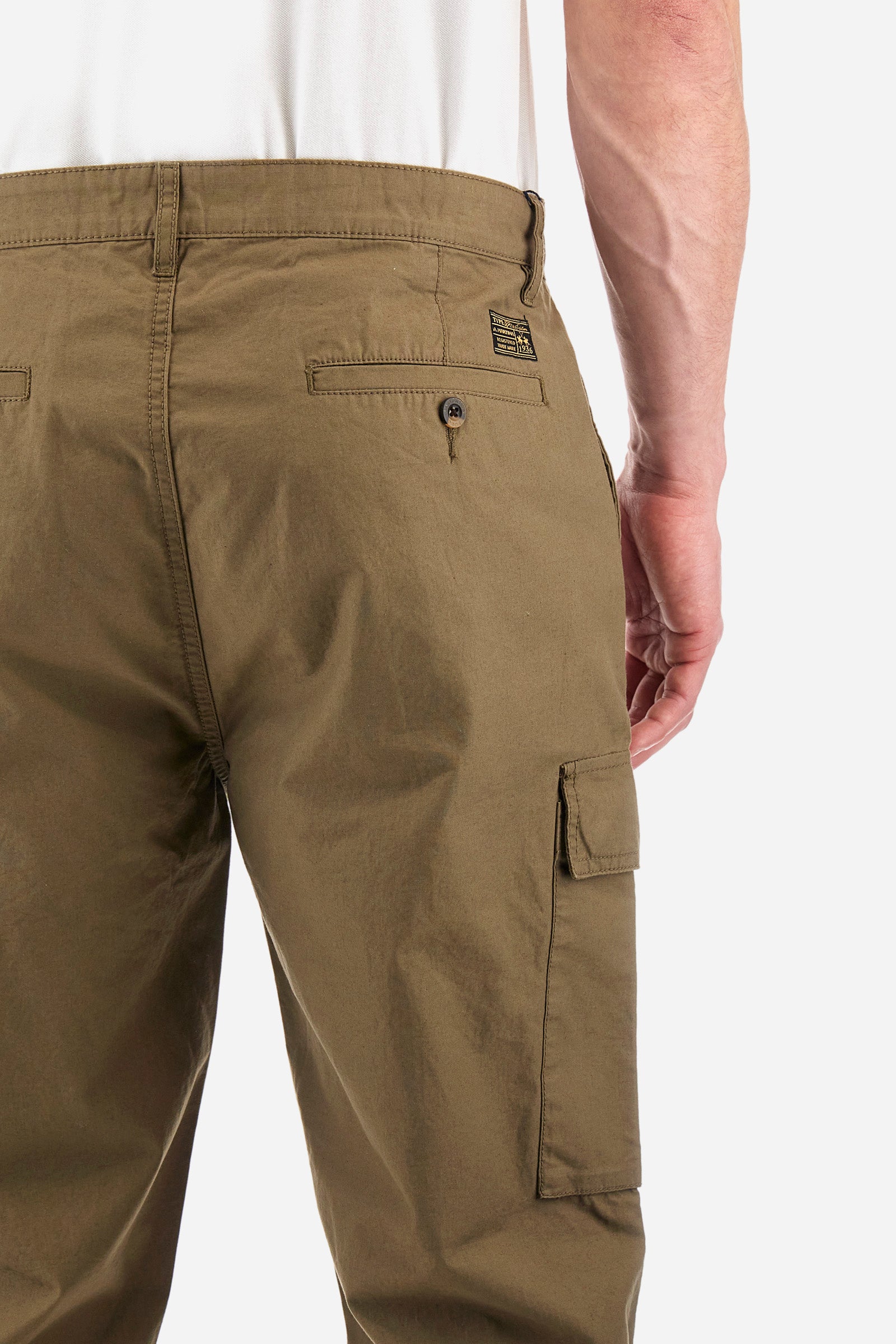 Men's single-colour cargo trousers in 100% cotton. With belt loops, zip and button fastening. There are two open pockets on the front, two cargo pockets with press stud fastening and two additional pockets on the back with buttonhole and classic button fastening. There is a logo with a patch sewn onto the reverse. The fit is regular. The model wears a size 33. - Military Olive