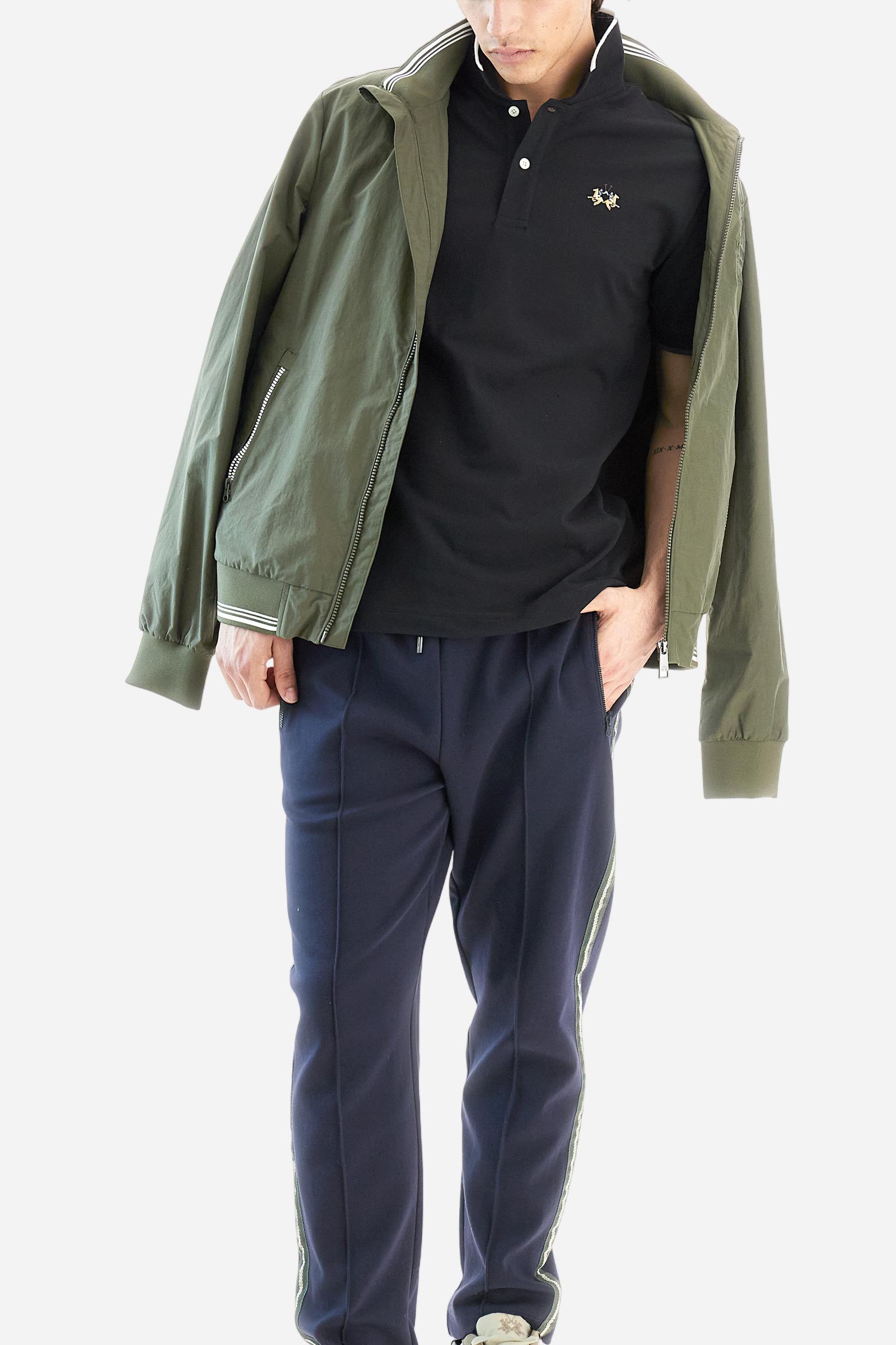 Short-sleeved, single-colour men's polo shirt made of stretch cotton piqué. Fastens with two buttons. The collar and cuffs are ribbed, and there is a colour-contrasting trim at the bottom of the collar. Inside the collar there is a grosgrain ribbon of a different shade. The logo is embroidered on the chest in a contrasting colour. The fit is slim. The model is wearing a size L. - Black