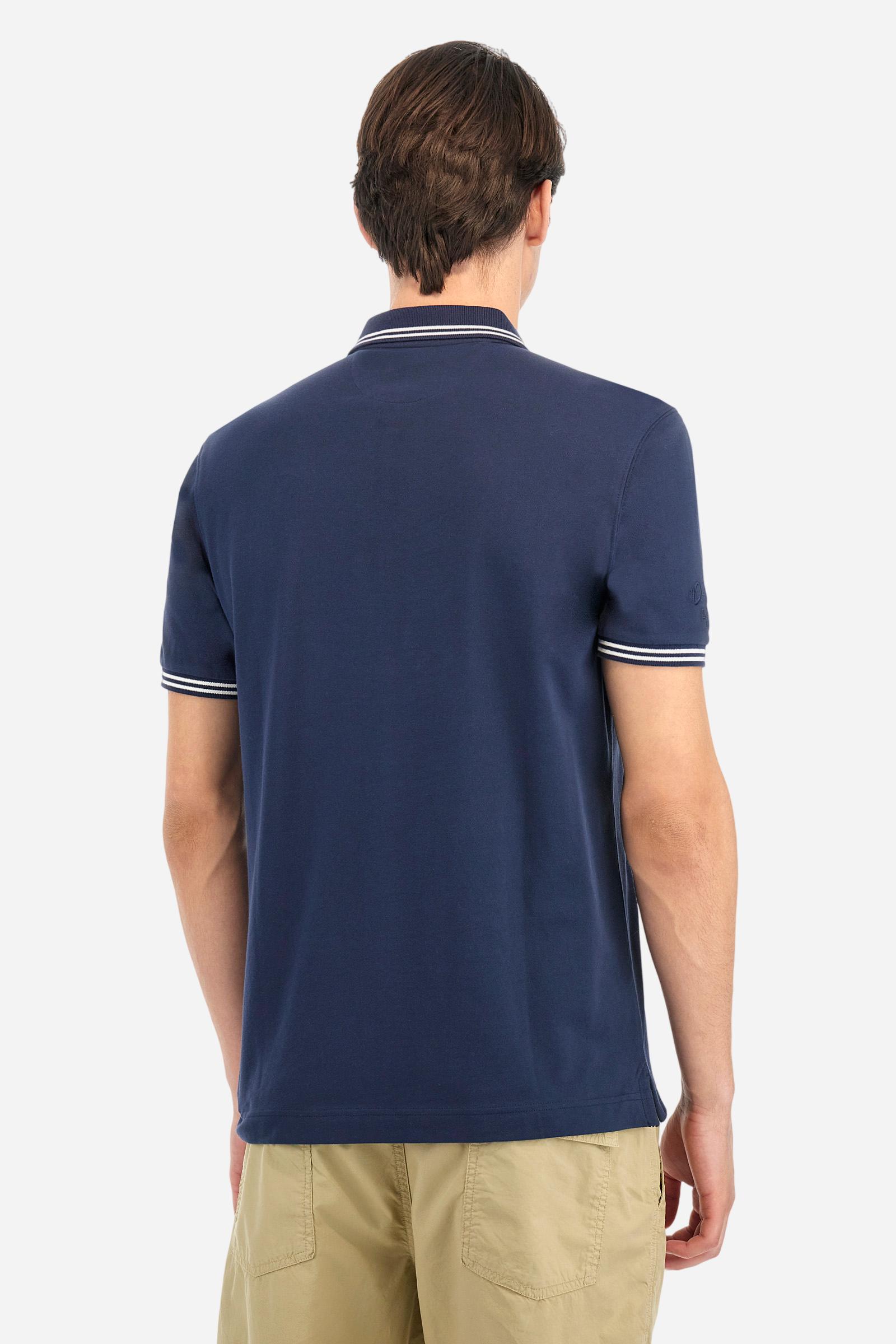 Men's plain short-sleeved polo shirt made from stretch piqué. Two-button fastening. The collar and cuffs are made from two-tone striped ribbed fabric. The inside of the collar and placket feature contrasting fabrics and colours. There is a two-tone striped band around the inside of the collar. The right sleeve and chest are embroidered in tone-on-tone thread. A logo is embroidered on the left sleeve, also using tone-on-tone thread. Regular fit. The model is wearing a size L. - Navy