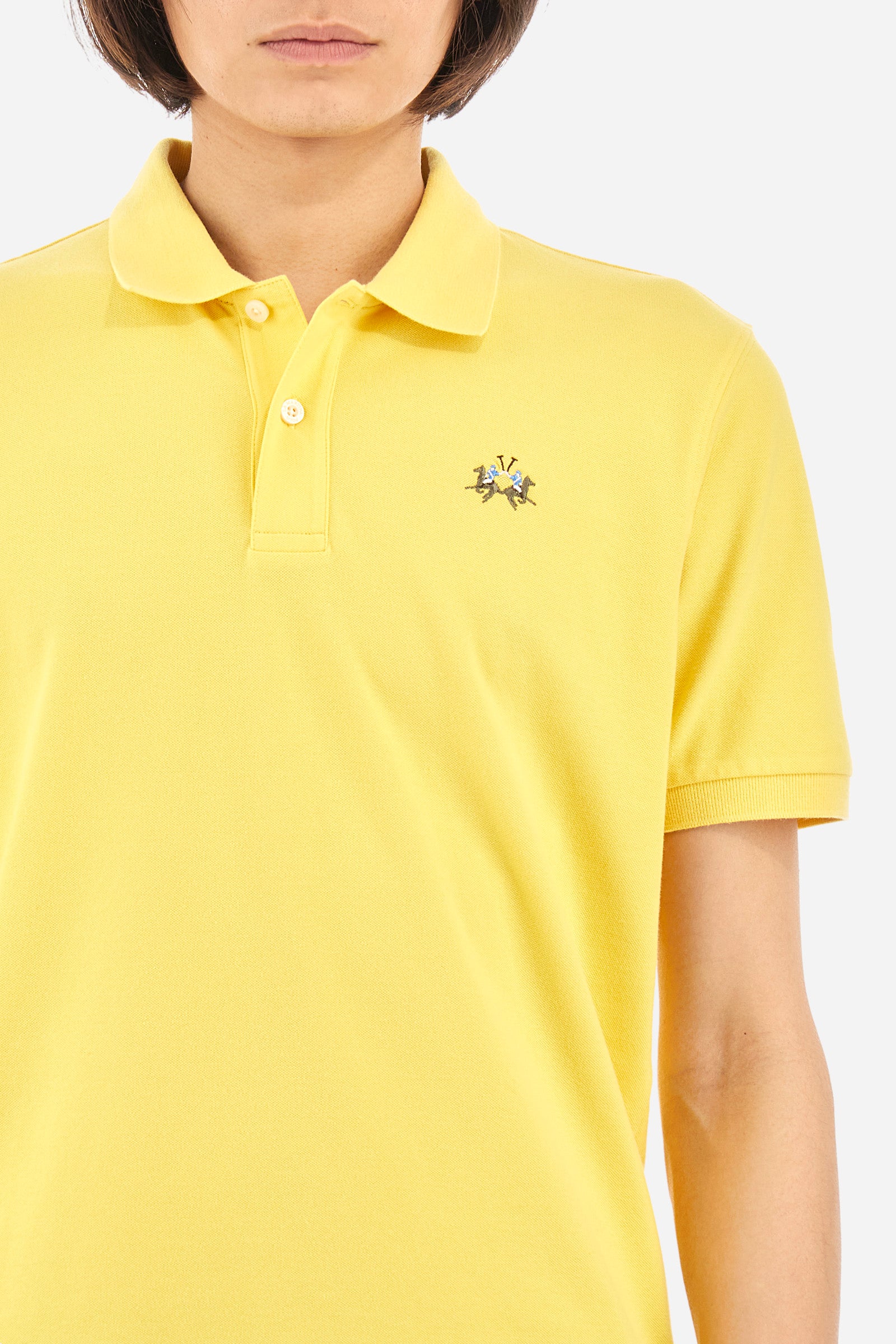 Men's single-colour short-sleeved polo in elasticated cotton. Two-button fastening. Tone-on-tone stitching. Ribbed collar and armholes. The "La Martina" lettering can be found under the collar. Featuring a small logo embroidered on the chest. In a slim fit. The model wears a size L. - Aspen Gold