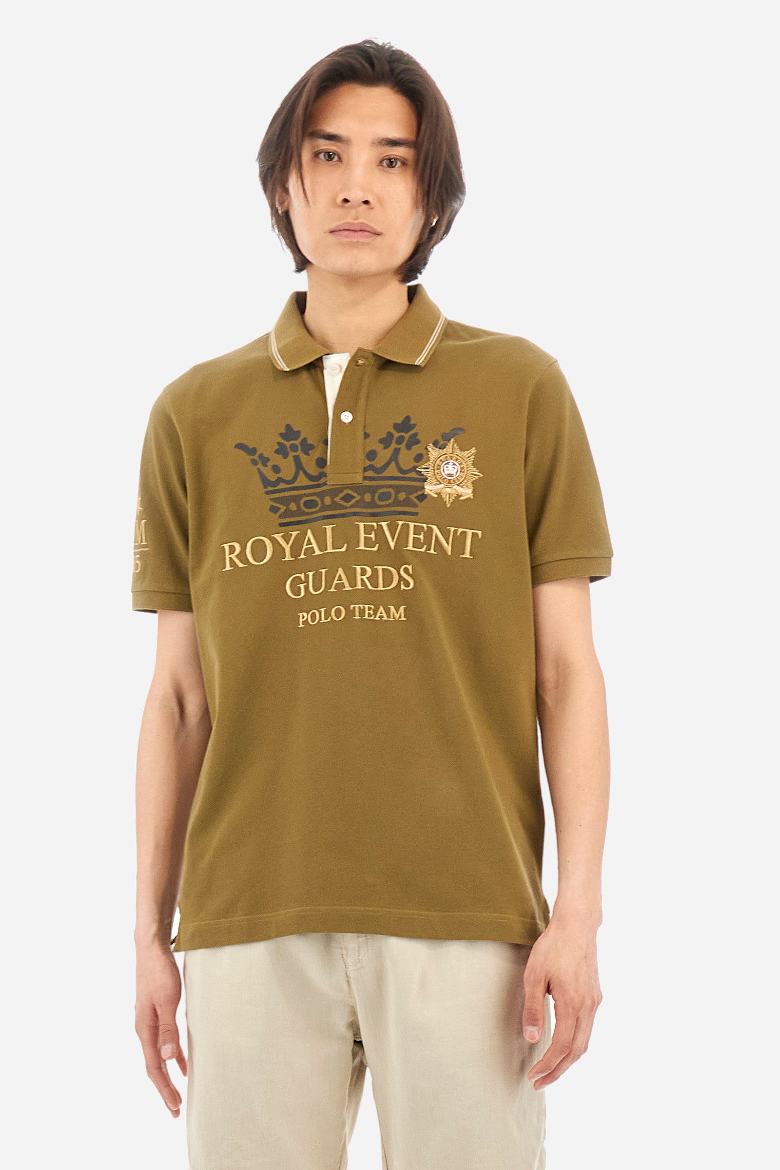 Men's single-colour short-sleeved polo shirt in 100% cotton. Two-button fastening. Collar with two contrasting stripes and ribbed armholes. On the front we find lettering and the symbol representing the Guards line. The brand's initials, the number 55 and the logo are embroidered on one of the sleeves. The fit is regular. The model wears a size L. - Military Olive