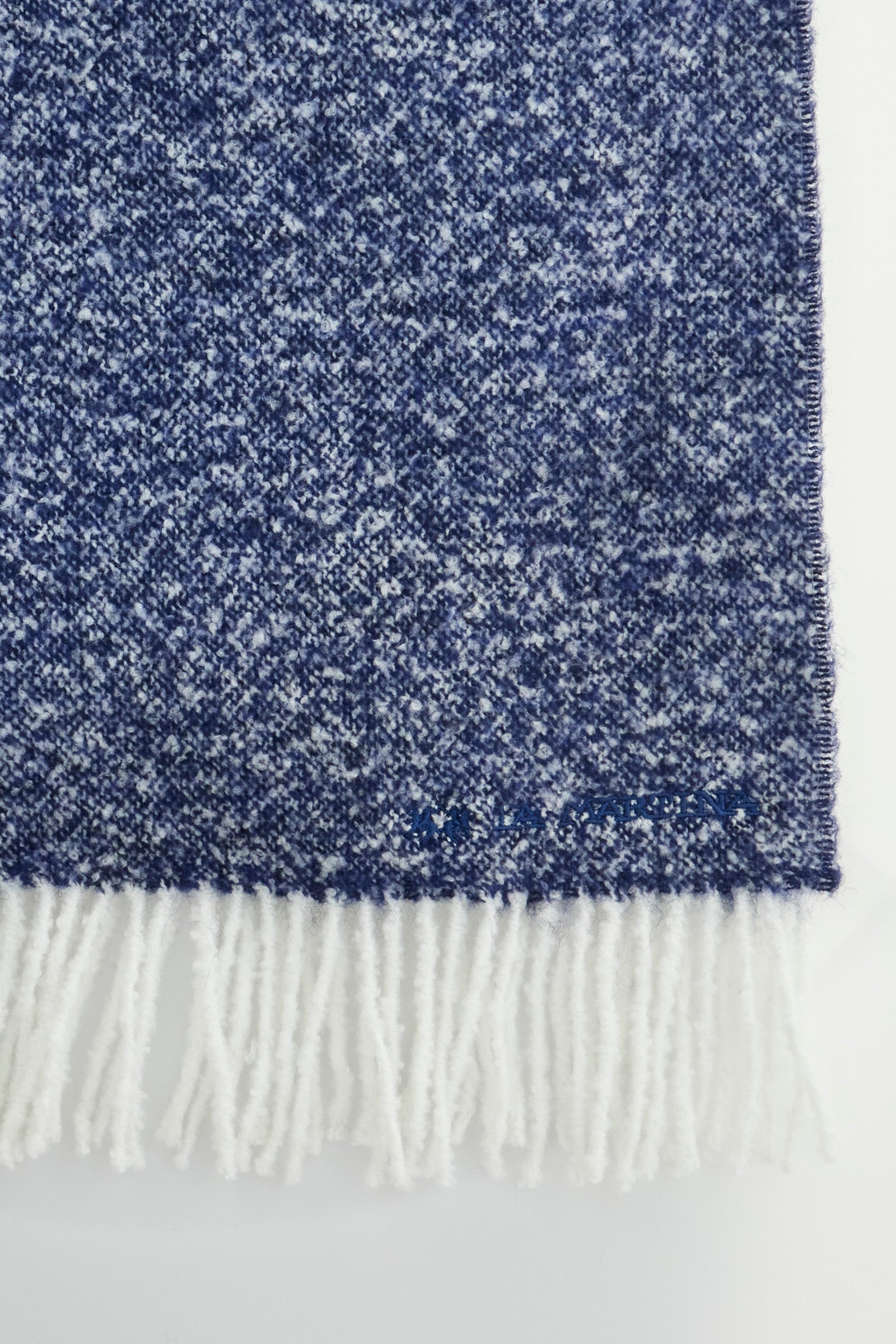 This scarf is part of an exclusive La Martina collection. It is made of grisaille wool blend, made in Italy. The solid tone is accompanied by fringes on the end in contrasting tone and mini logo and writing La Martina. Perfect to embellish your winter outfit with a touch of sophistication. Dimensions: 42x190 cm. - Navy