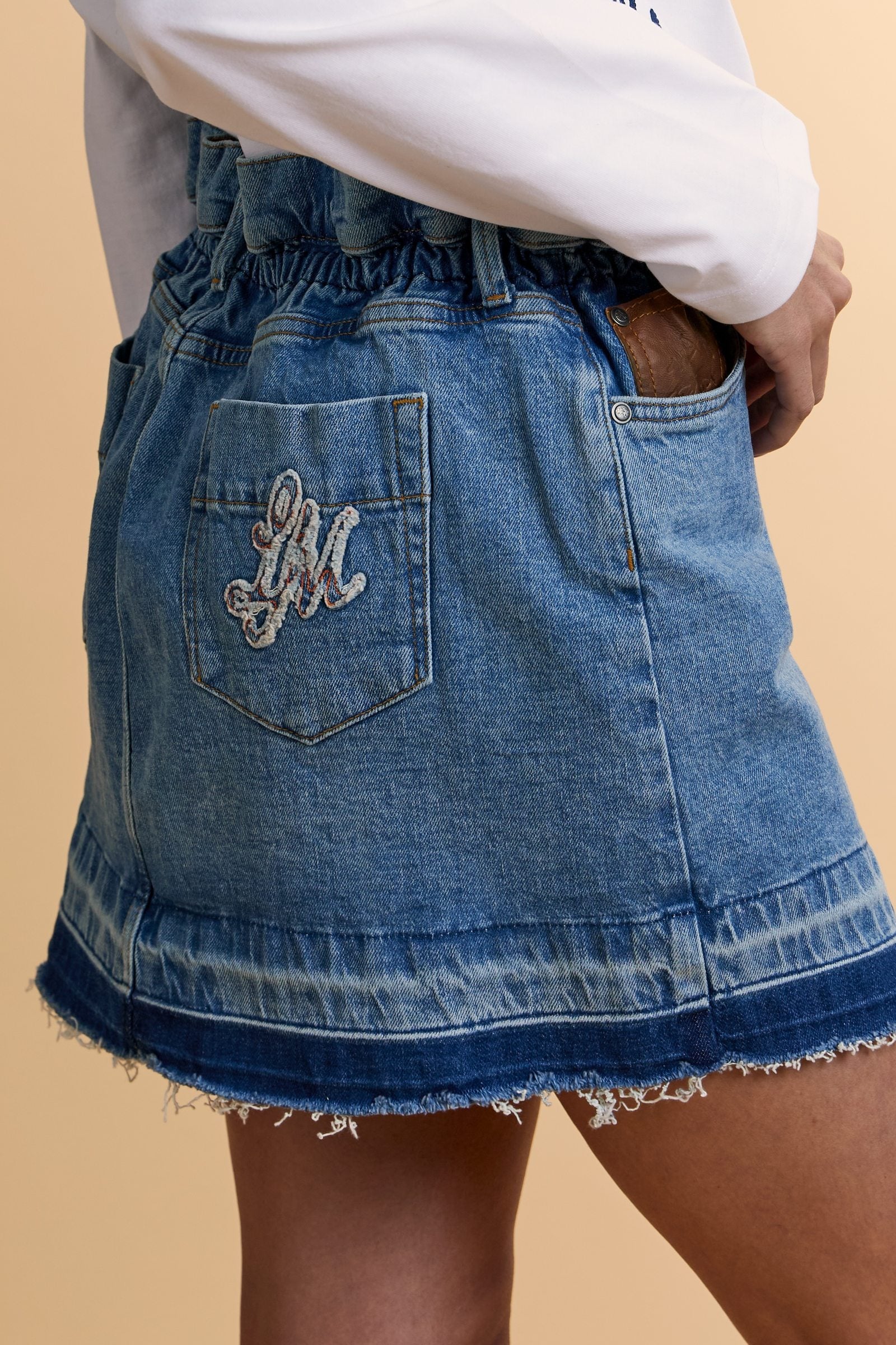 Denim mini skirt with light-medium wash and worn-in effect. Slightly flared five-pocket style with raw-cut hem and contrast pocket with logo. - Medium Indigo Denim