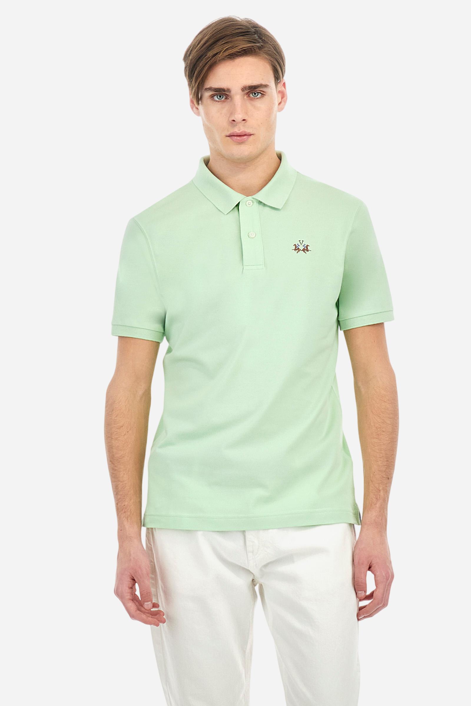 Men's plain short-sleeved polo shirt made from stretch piqué. Two-button fastening. The collar and cuffs are made from tone-on-tone ribbed fabric. Under the collar, there is a contrasting fabric panel with embroidered multicoloured lettering. The logo is embroidered on the left side of the chest in contrasting thread. Slim fit. The model is wearing a size L. - Pastel Green