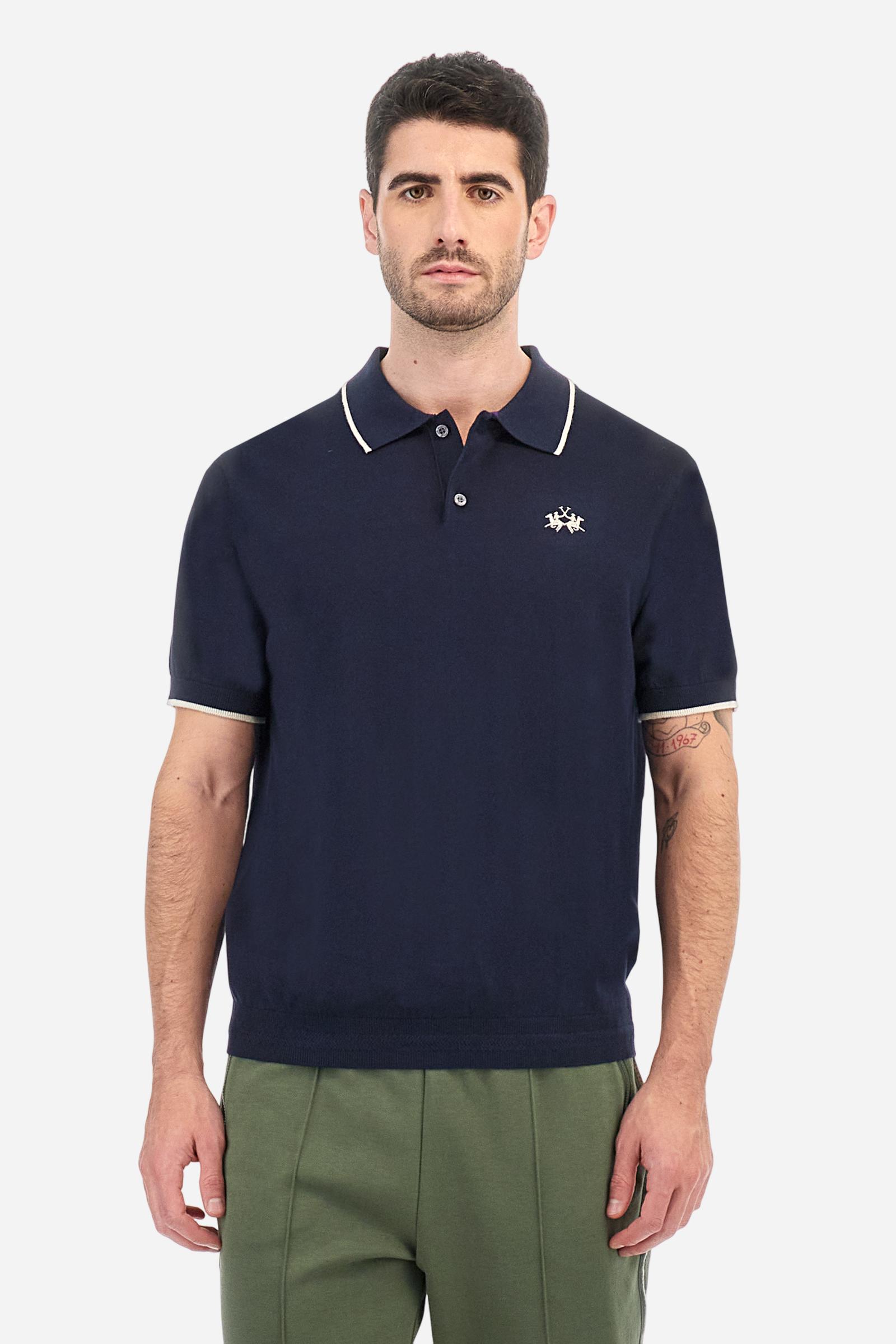 Single-colour men's polo shirt with short sleeves. Made of knitted cotton yarn. Two-button fastening and ribbed collar with contrasting stripes on the bottom. The cuffs of the sleeves are ribbed, as is the band at the bottom, which is embellished in the centre with a band featuring a herringbone stitch. A contrasting coloured jersey ribbon is applied to the inside of the collar. The logo is embroidered on the left side of the chest in contrasting thread. Regular fit. The model is wearing a size L. - Navy