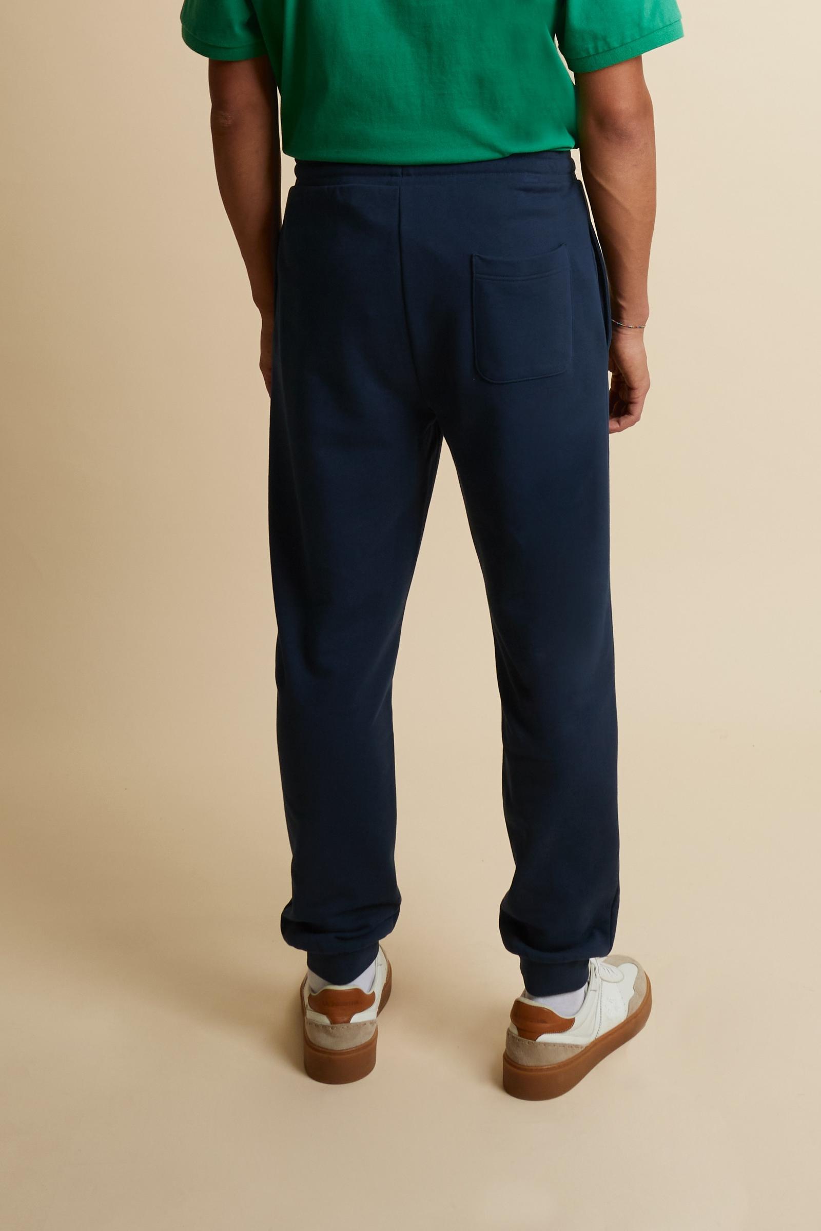 Men’s jogger pants made of soft solid color 100% cotton summer fleece. Minimalist design with tapered cut, comfortable on hips and thighs and slightly narrower toward the hem for a modern, streamlined silhouette. Featuring side slash pockets and adjustable waistband with flat drawstring. Small contrast embroidered brand logo below the left pocket. The model wears size L. - Navy