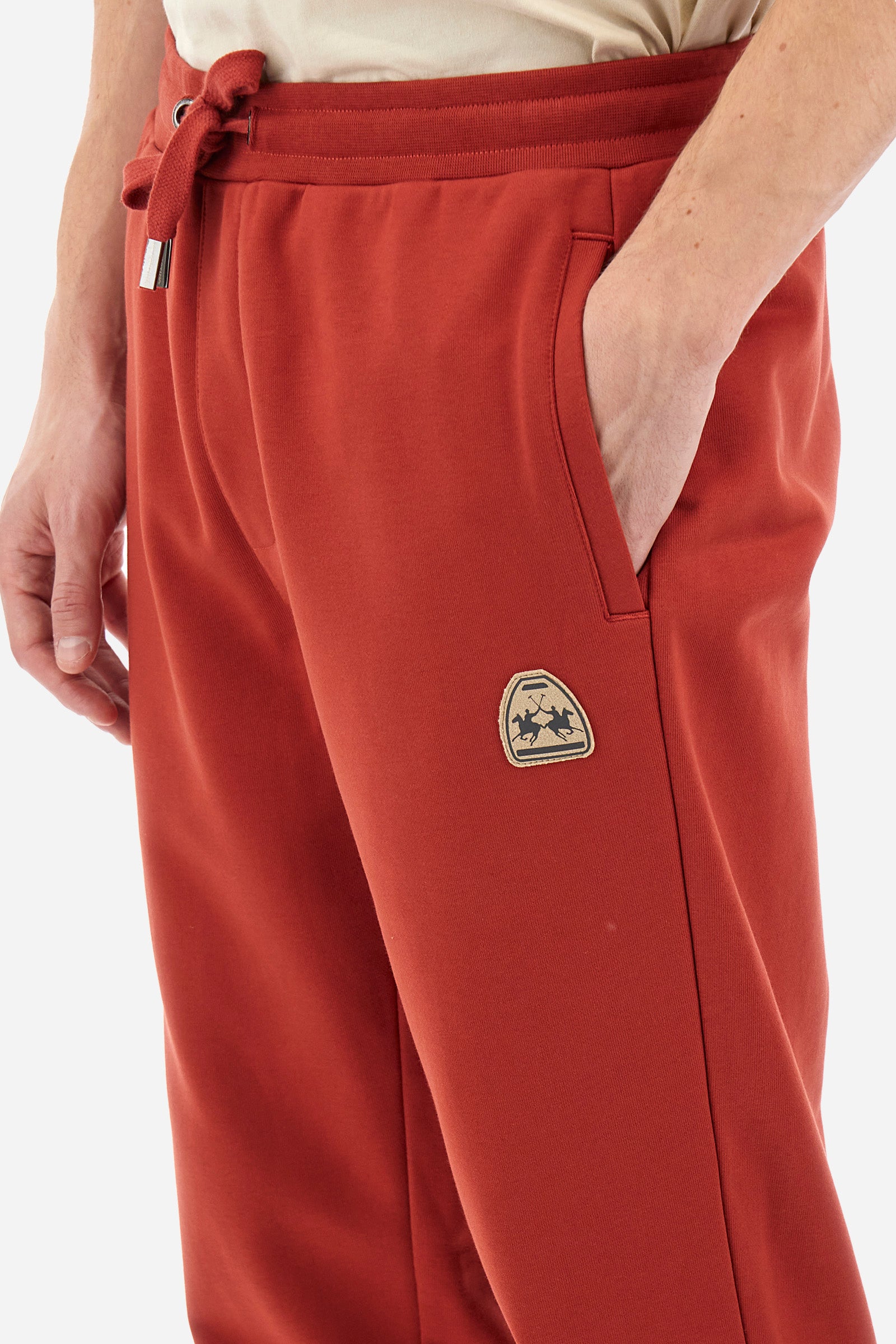 Men's single-colour jogging bottoms in a cotton sweat fabric from the Polo Academy line. With a drawstring waist and double front pocket. Another pocket is present on the back. The logo is present on a patch applied under one of the front pockets. The fit is regular. The model wears a size L. - Cinnabar