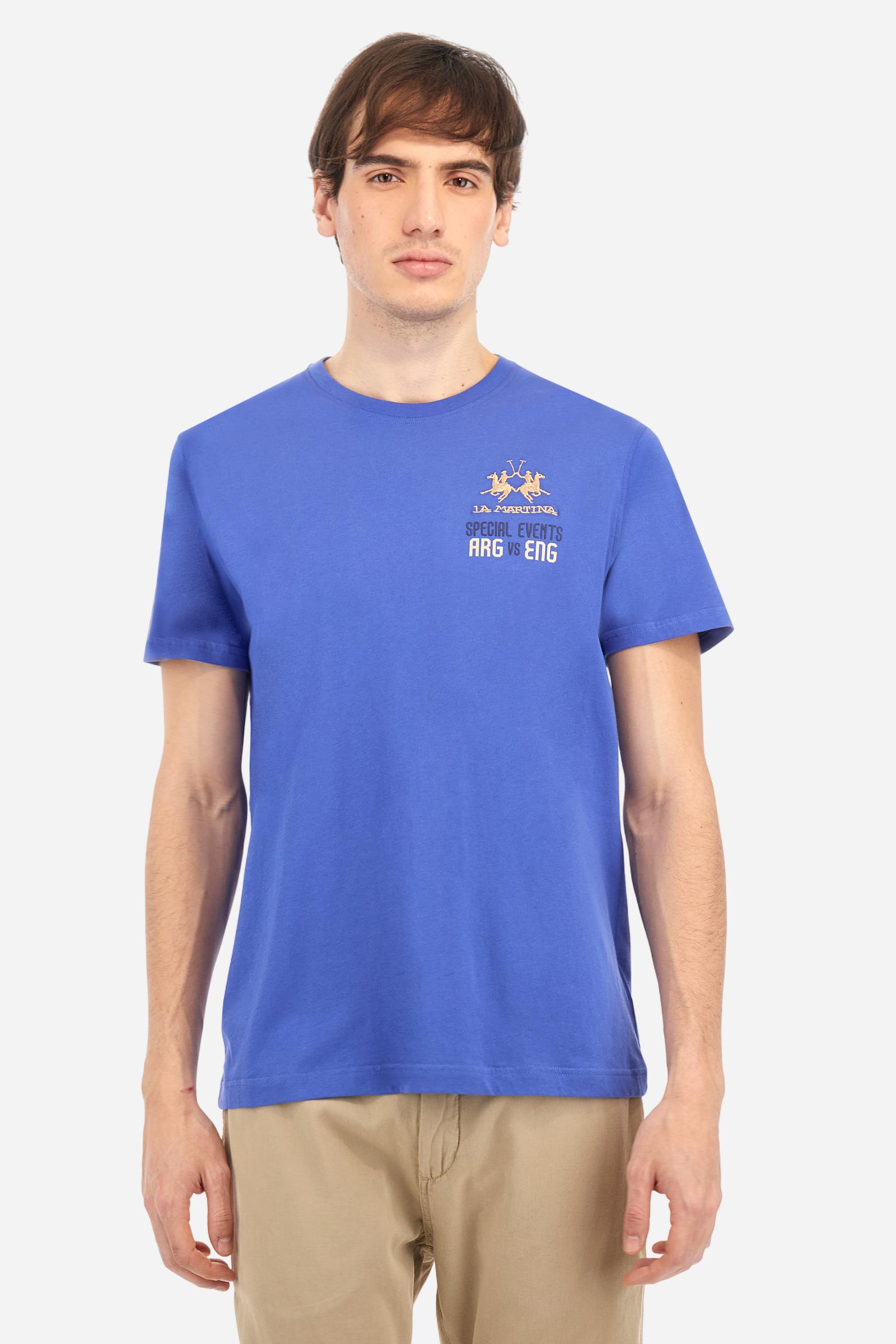 Men's plain cotton jersey short-sleeved T-shirt. Ribbed crew neck. On the front, left side, there is a two-tone embroidery inspired by the polo events played between Argentina and England. On the back, the printed graphic plays with the two flags, celebrating the Dubai and La Martina polo teams with contrasting coloured writing. The logo is embroidered on the left side of the chest in contrasting thread. Regular fit. The model is wearing a size L. - Dazzling Blue