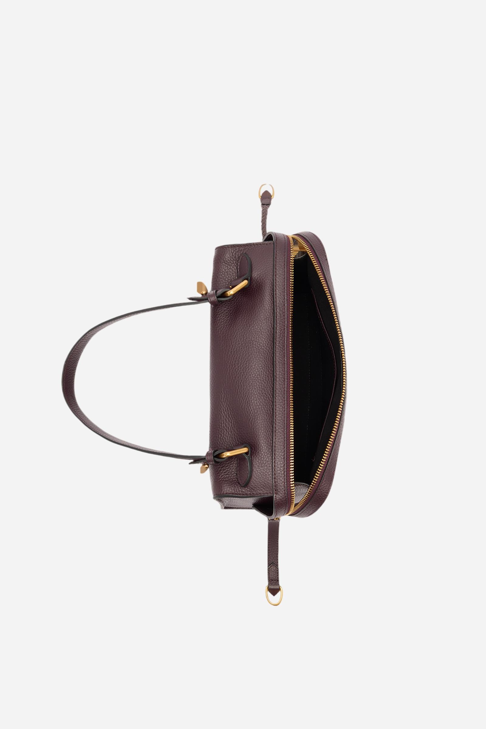 Compact shoulder bag made of high-quality full-grain leather. The double side zip with long leather pullers creates both functional and decorative detail. The slightly trapeze silhouette and the gold metal logo plaque define its distinctive and elegant character. Dimensions:28 x 22 x 12 - WINE